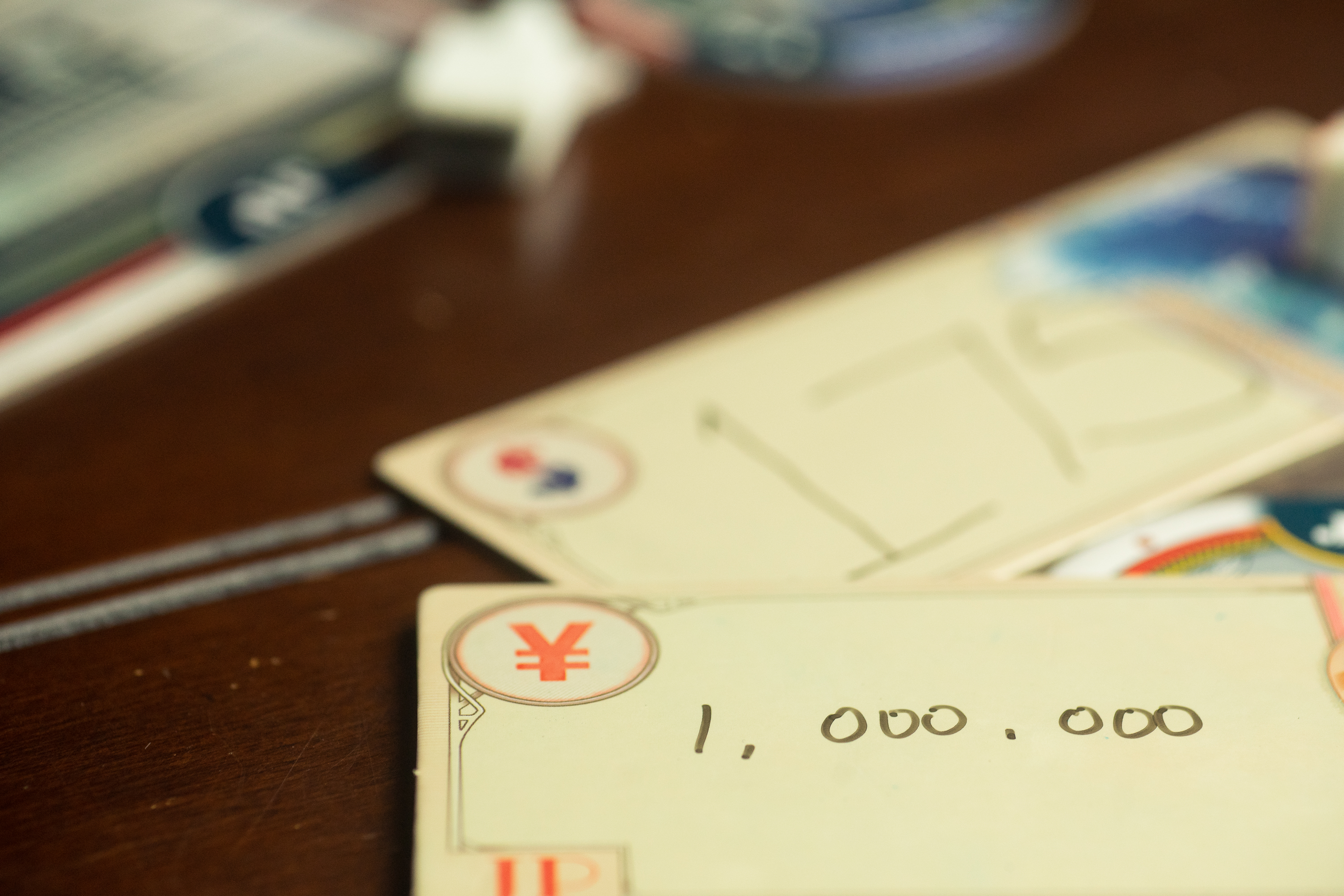 Tiles from the game QE on a table. One player has bid 1,000,000; another has bid 175.