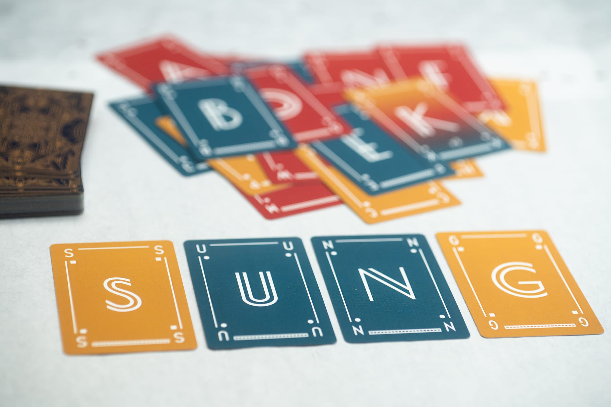 The card game LetterTricks on a table. The player has spelled the word SUNG.