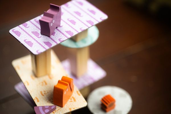 Small wooden cats stand on thin cardboard t