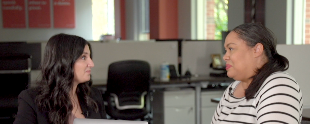 A Black woman and a White woman having a conversation in an office