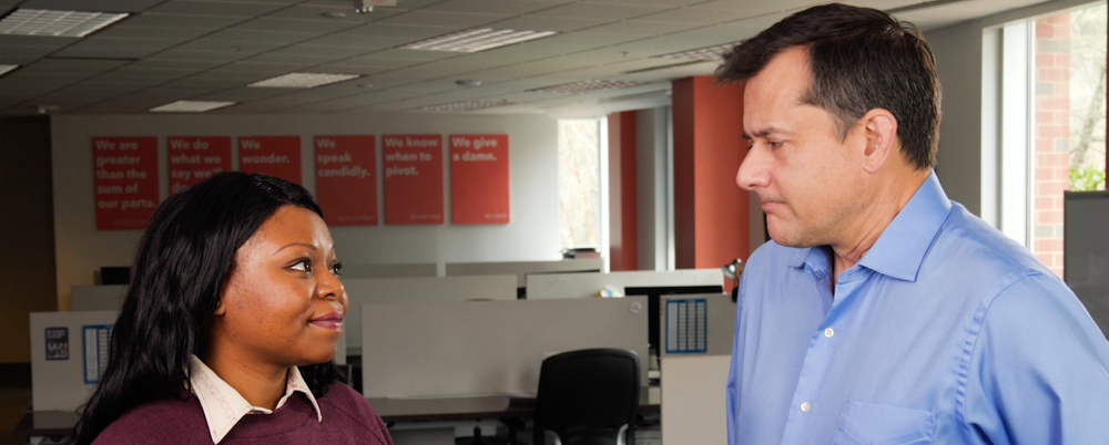 A Black woman and a White man having a conversation in an office