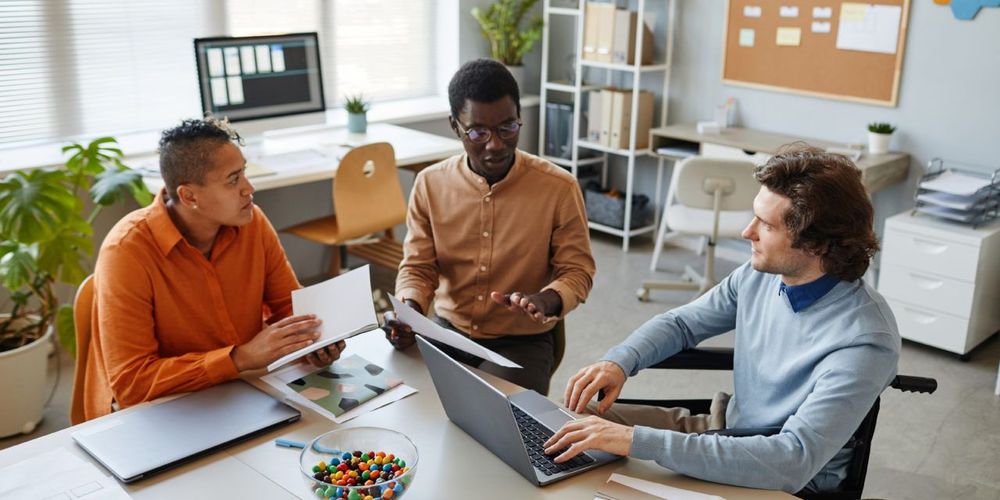 Portrait of diverse business team discussing project at meeting table focus on young man using wheelchair