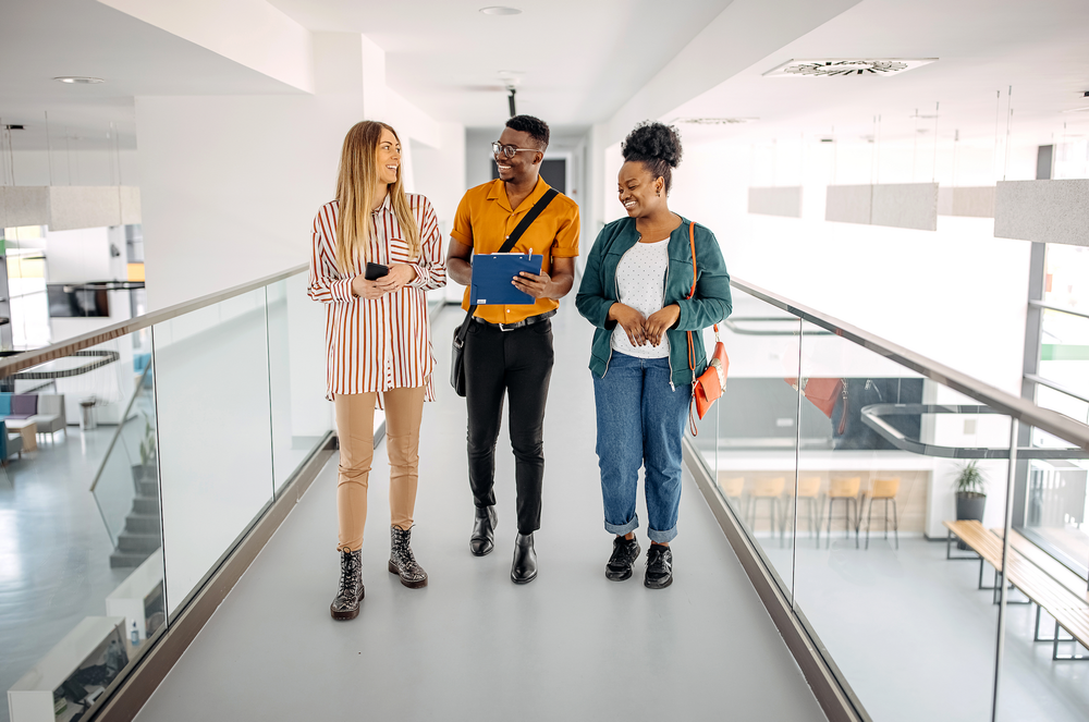 Young trainees walking in office hallway and discussing ideas