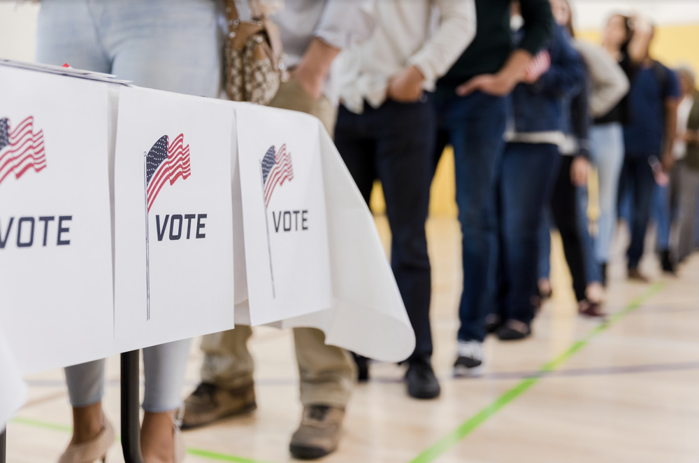 A low angle view of a long line of people waiting to vote in the elections.