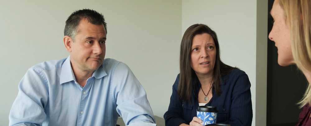Three people sitting at a table looking concerned