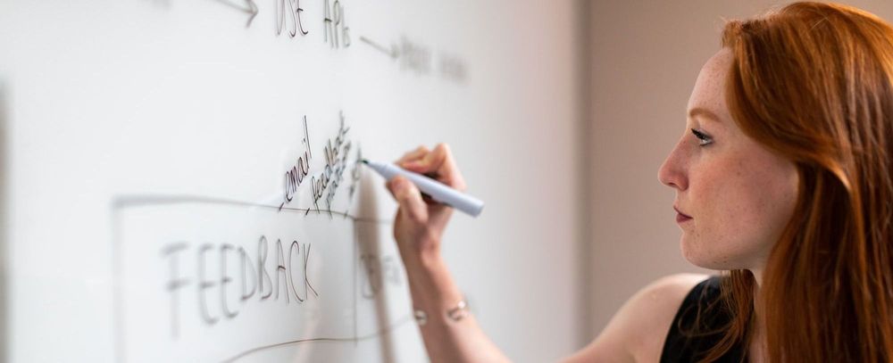 Woman with red hair writing on a white board