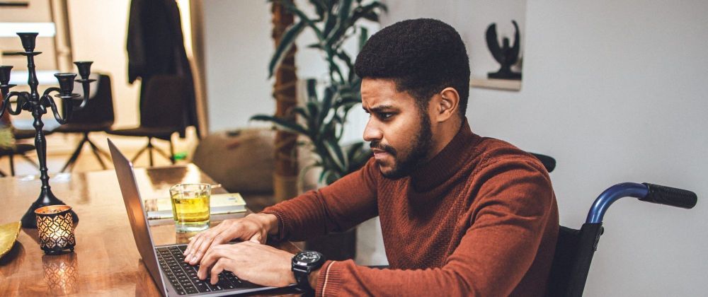 Disabled young African-American male meeting the deadline working at home using laptop.