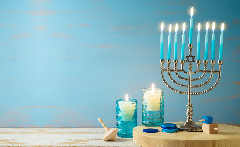 Jewish holiday Hanukkah concept with menorah, candles and dreidel on wooden table.