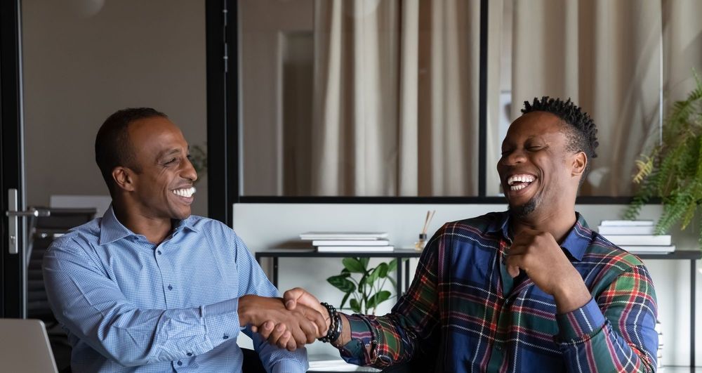 Two Black men shake hands in an office