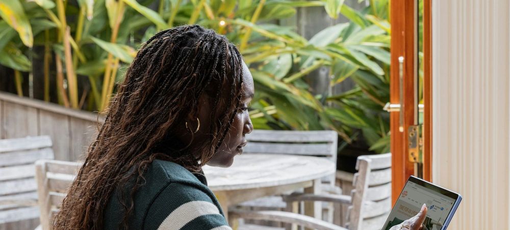 Woman with dark skin and braids looking at a laptop
