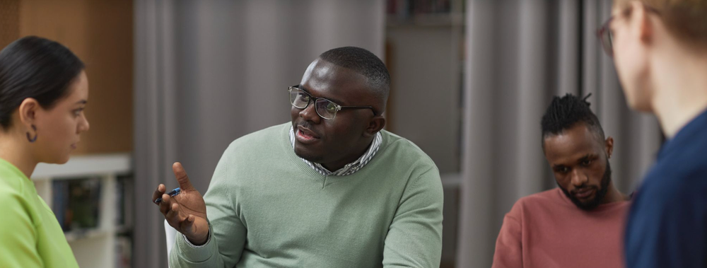 Black man with short hair wearing a green sweater in a mental healthcare setting