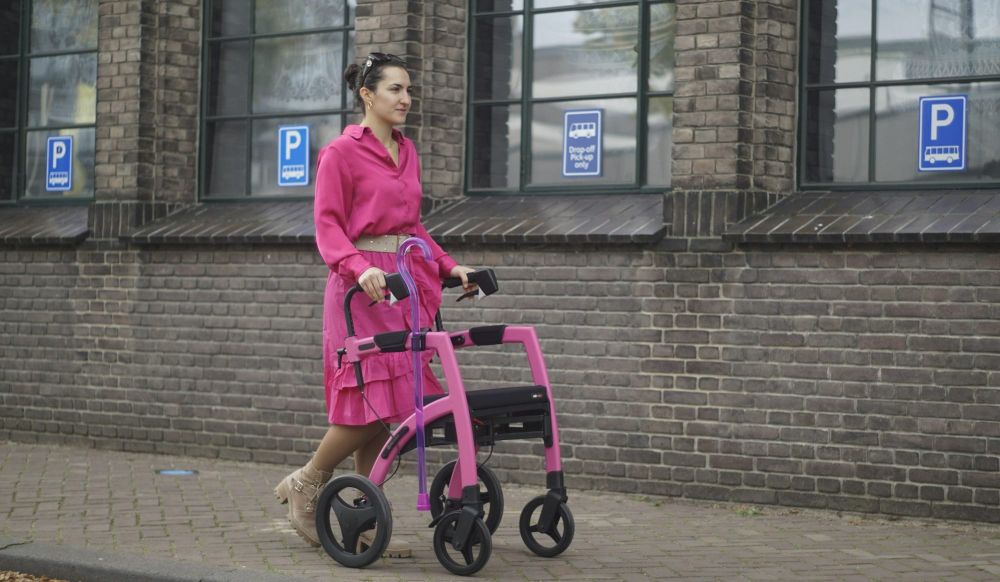 A professional woman uses a walker as she strolls outside on a city street.
