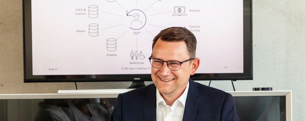 A man executive with short brown hair smiles at the camera