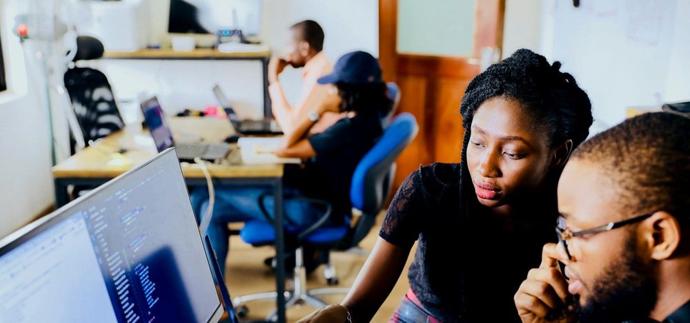 Two Black employees discuss coding