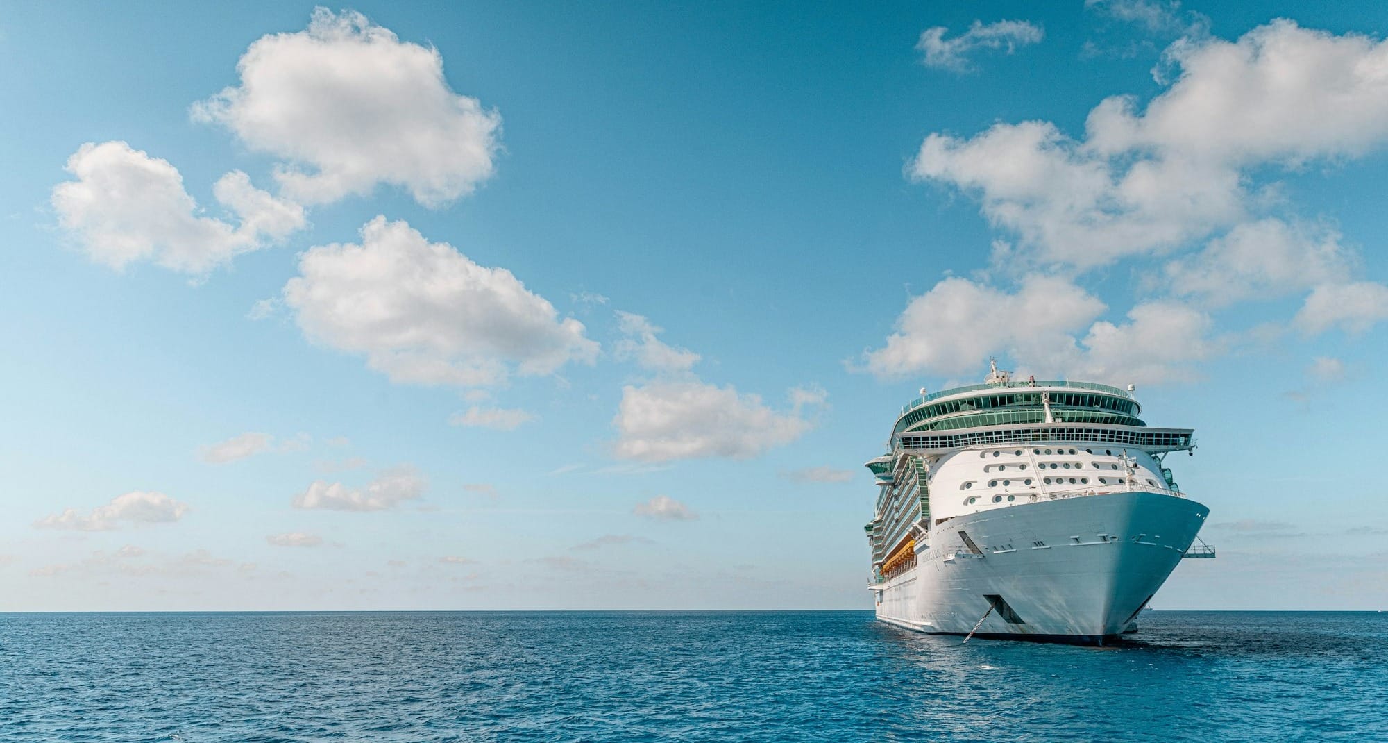 white and blue ship on sea under blue sky and white clouds during daytime