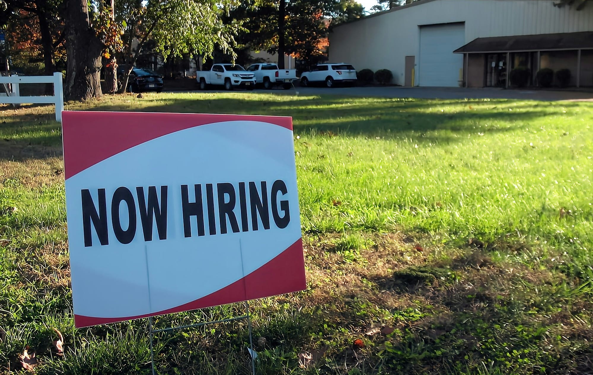 a now hiring sign in front of a building