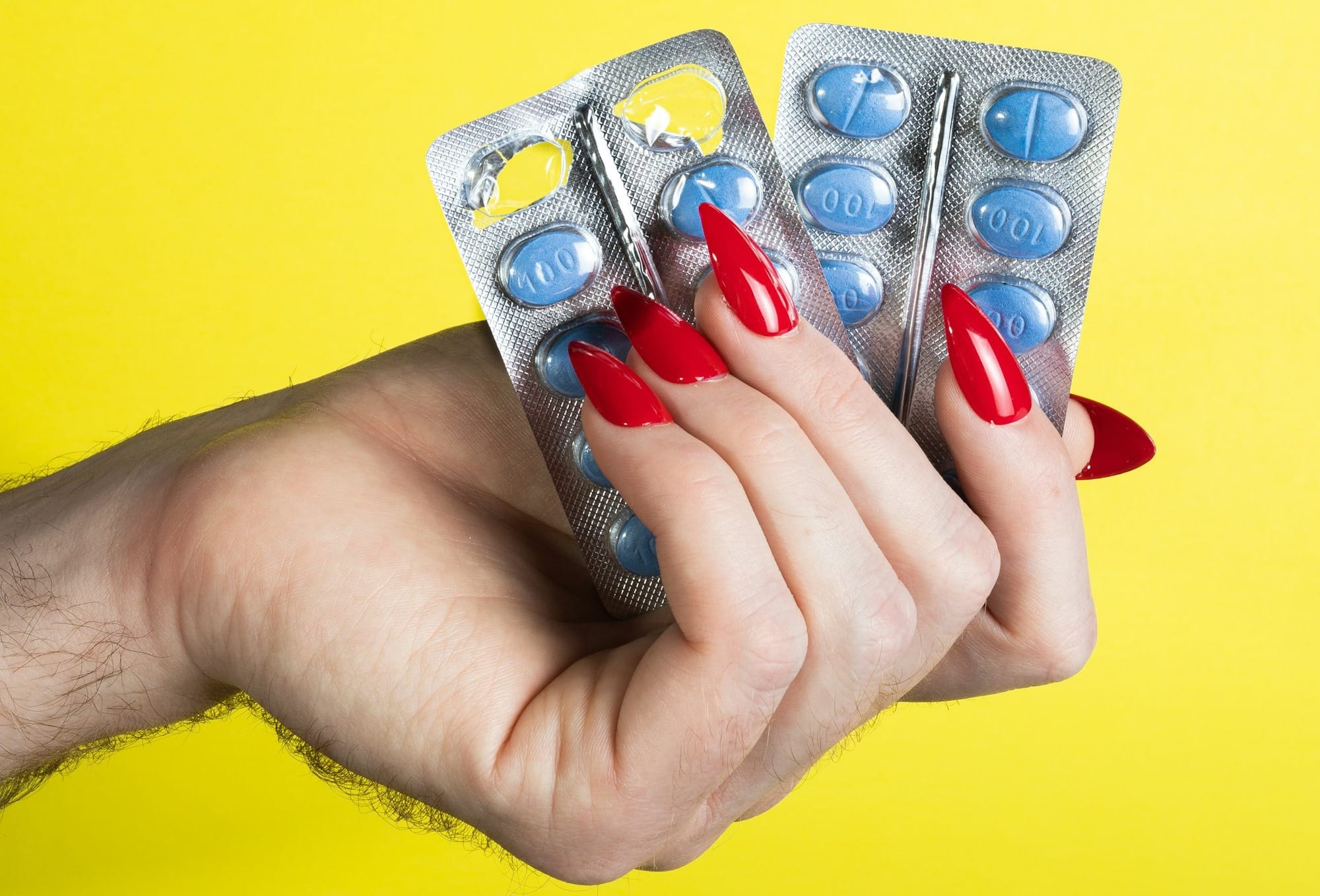 a woman's hand holding two contraptions in front of a yellow background
