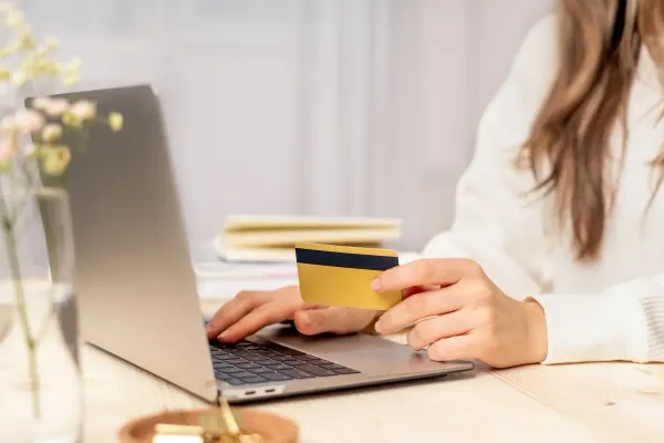 Florist using a credit card while working on a laptop.
