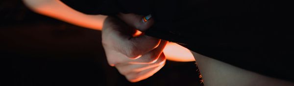 A hand, with pride nail varnish, lifts a piece of fabric on another body part