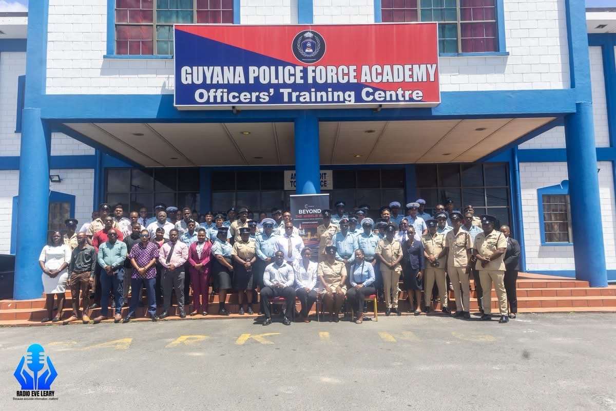 The graduating class outside the Guyana Police Force Academy's Officers' Training Centre, 6 August 2026. A Beyond The Wheels 2.0 banner stands at the centre of the group.