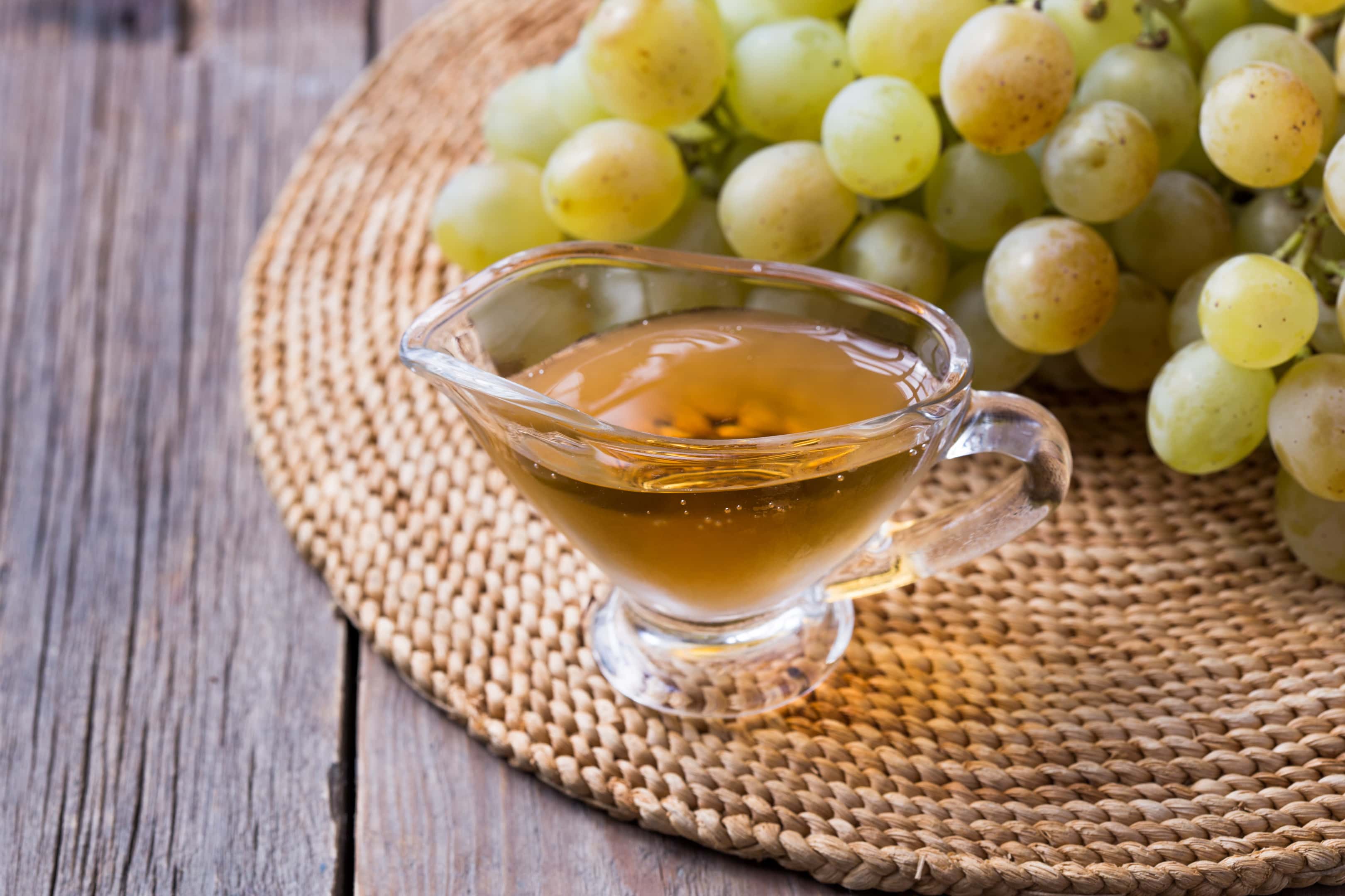 White wine vinegar in a glass jug on vintage wooden surface