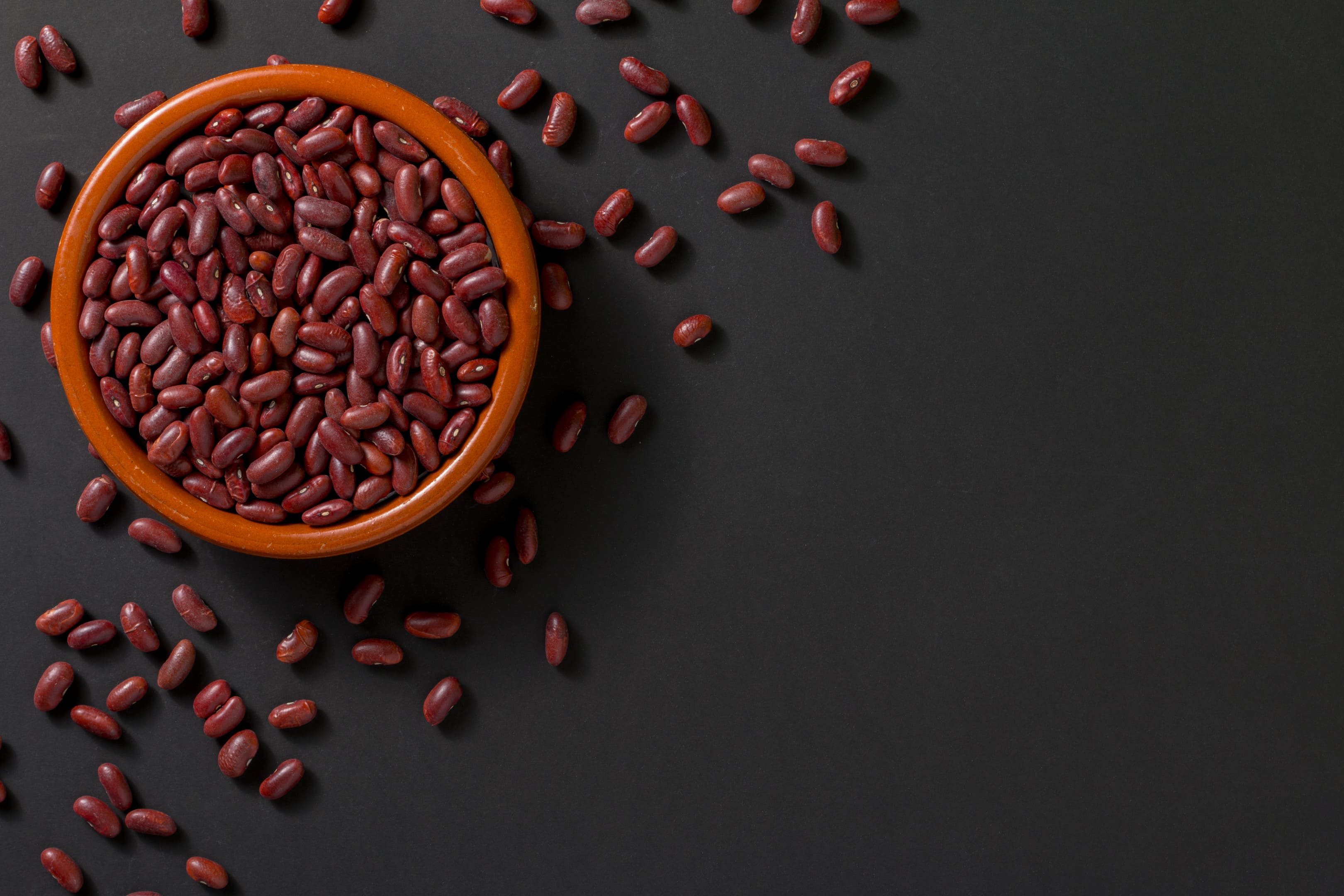 Bowl with red beans on black background