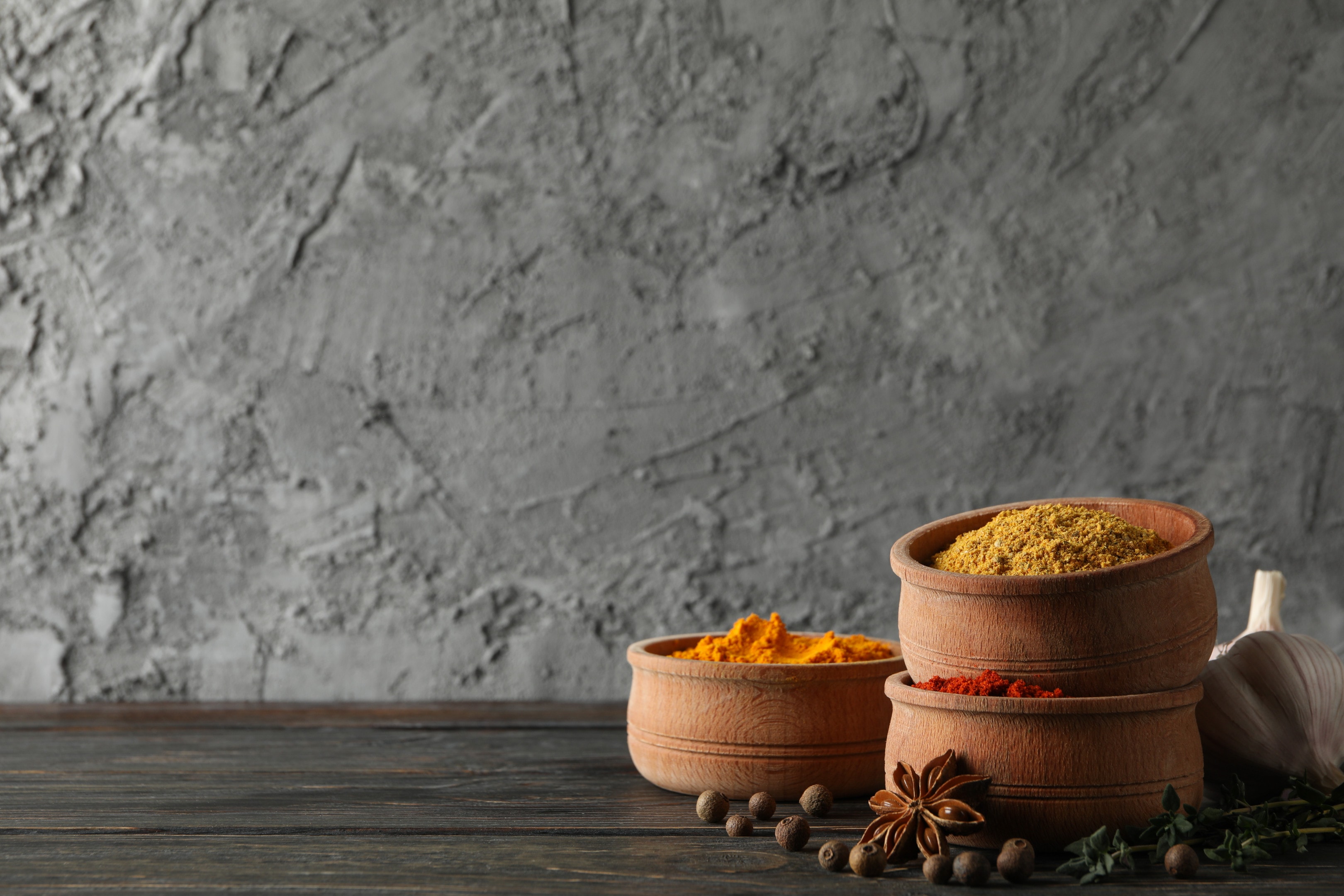 Bowls with different masala curry powders on wooden background