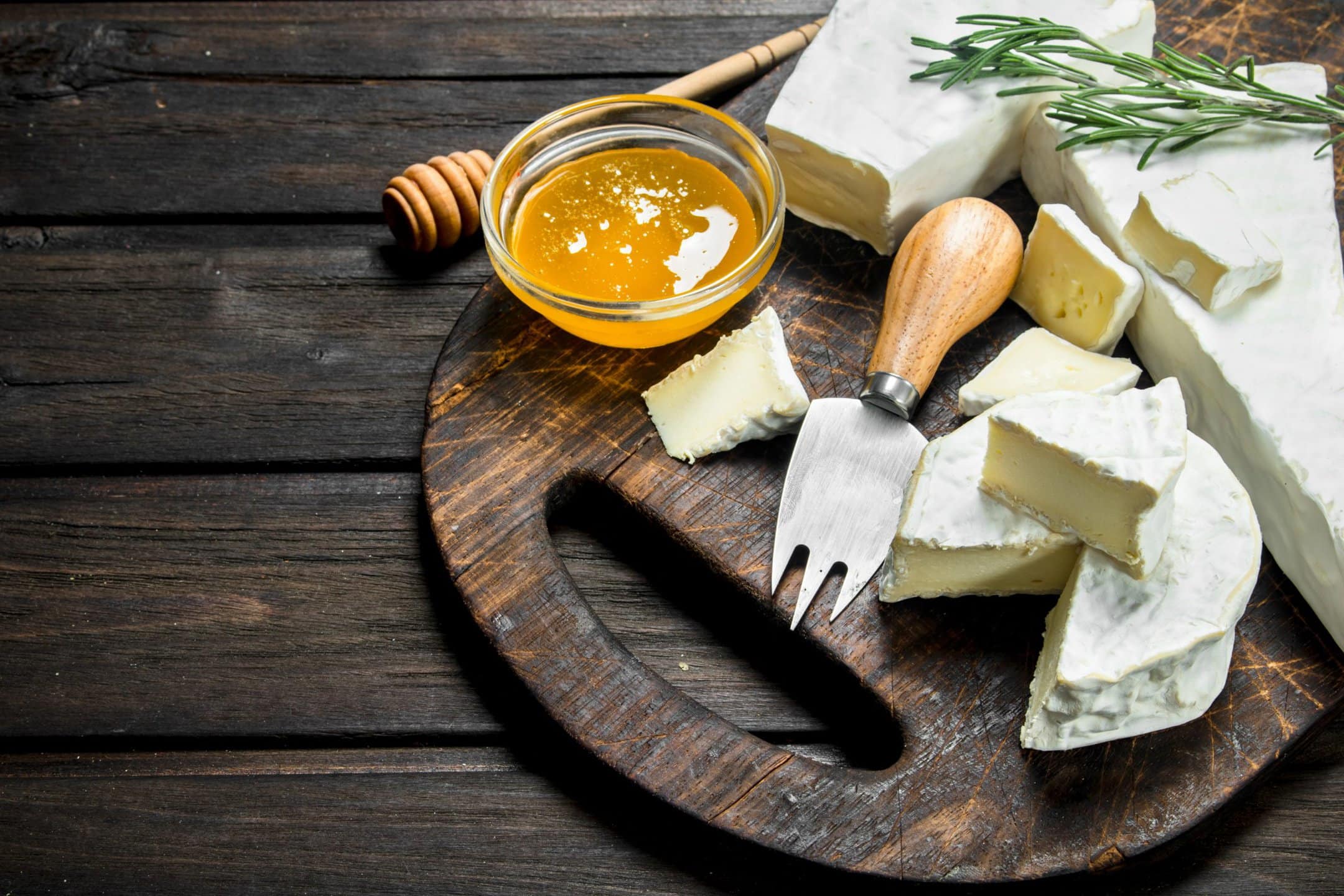 Brie cheese with honey and rosemary on a cutting board