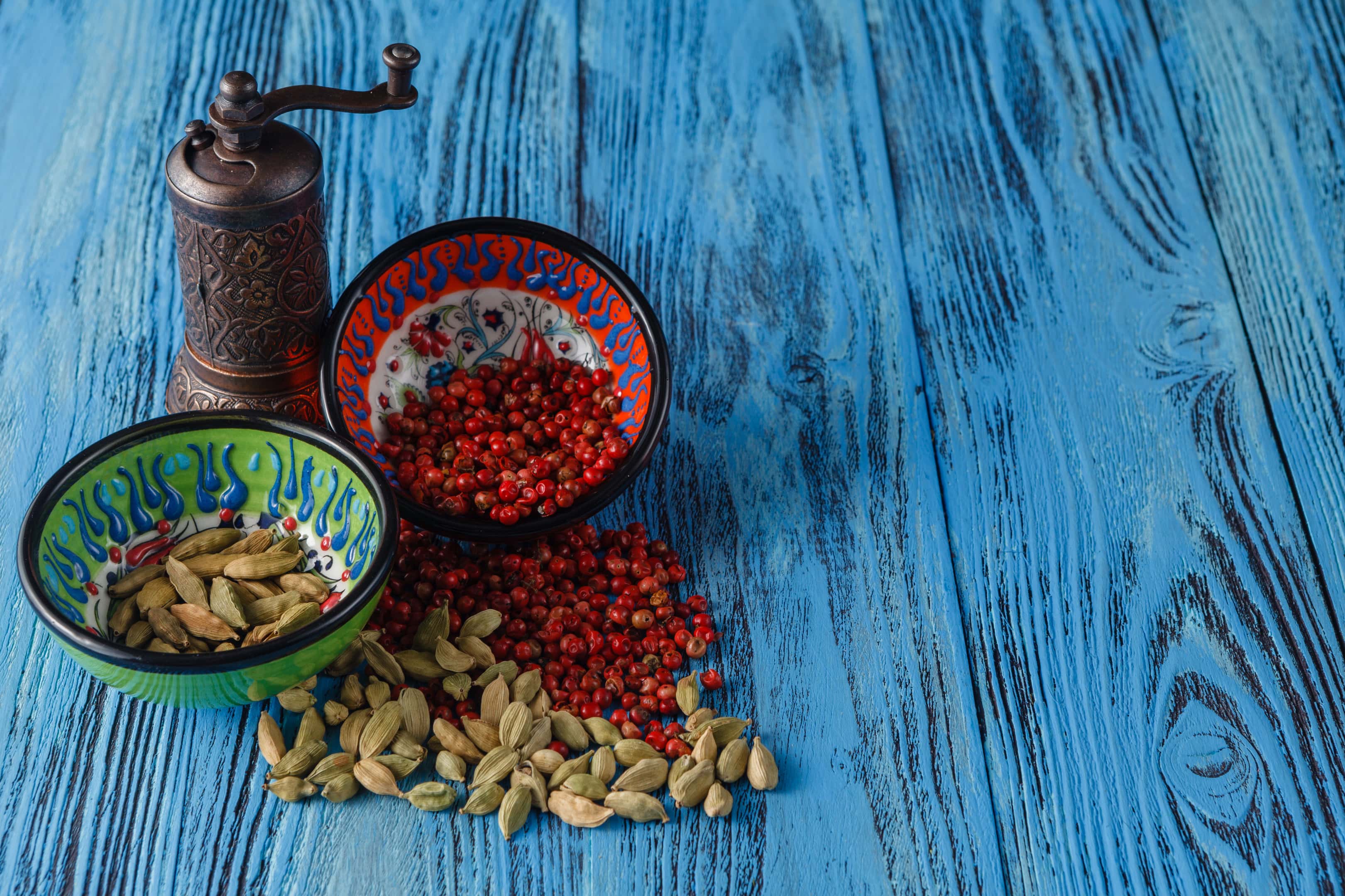 Cardamom and peppercorn in bowls on wooden table