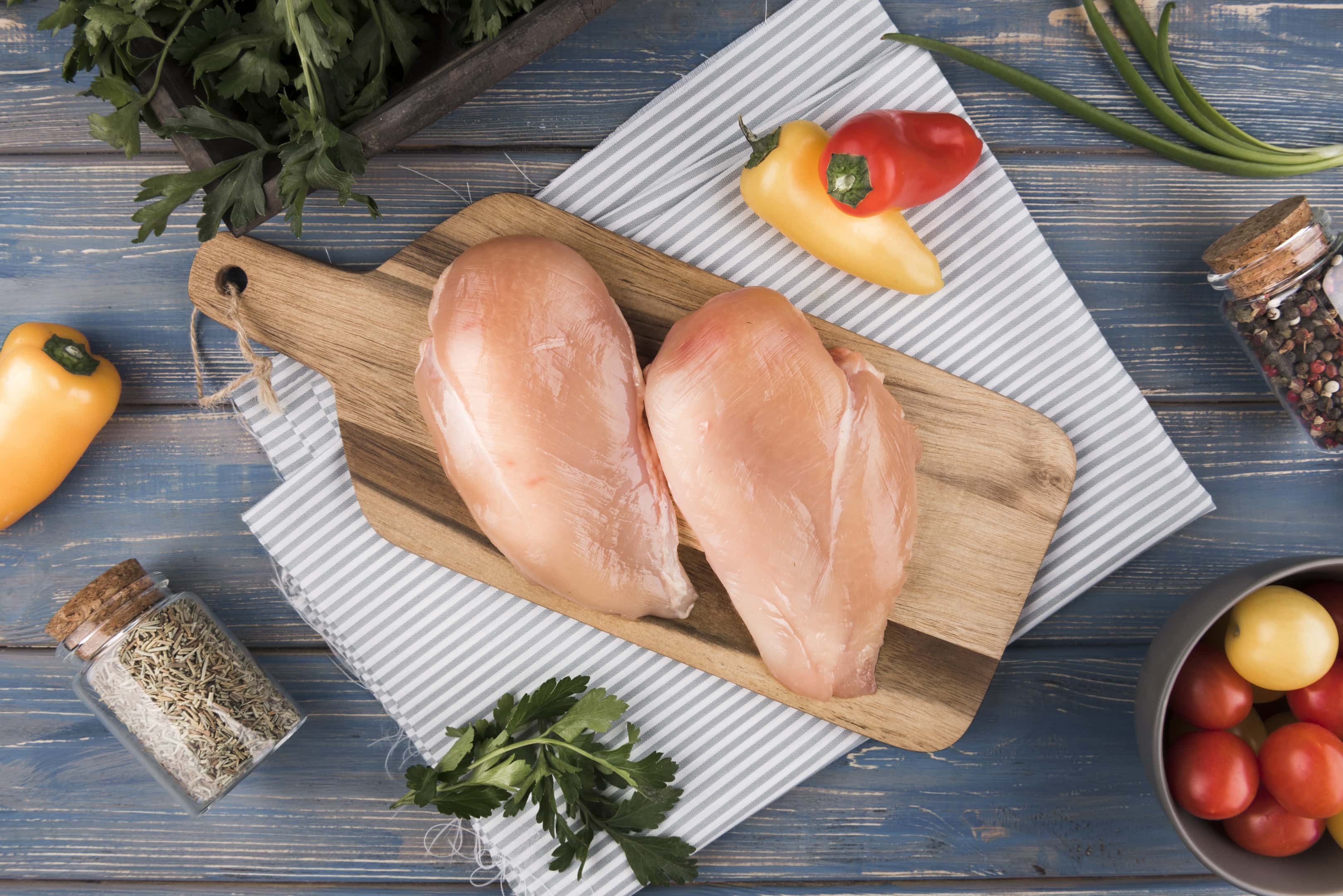 Chicken breasts on wooden board with ingredients