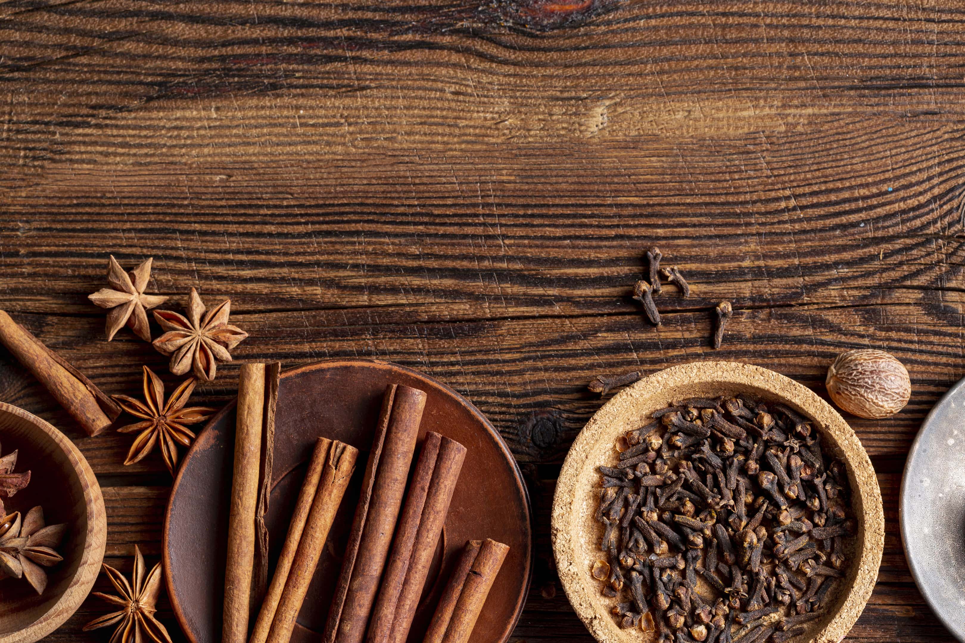 Cinnamon and cloves in bowls on wooden table
