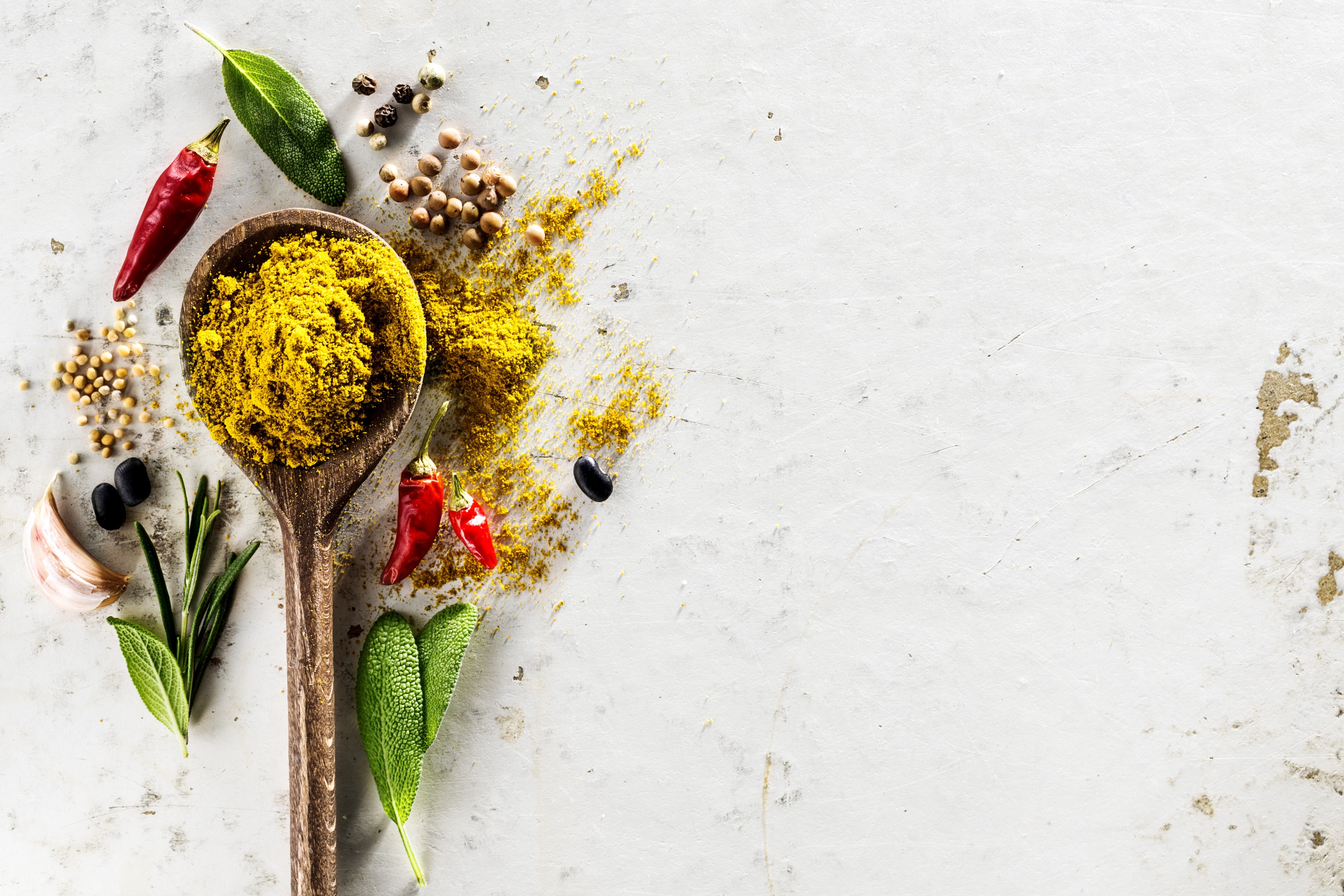 Dried herbs and spice blend with wooden spoon on white table