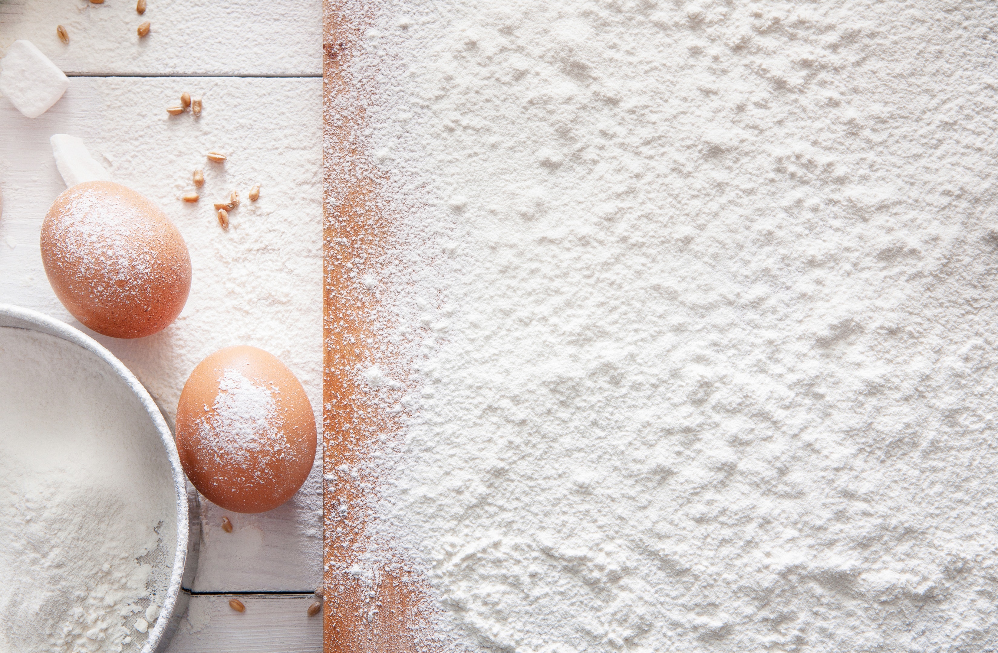 Eggs sprinkled with wheat white flour on wooden board