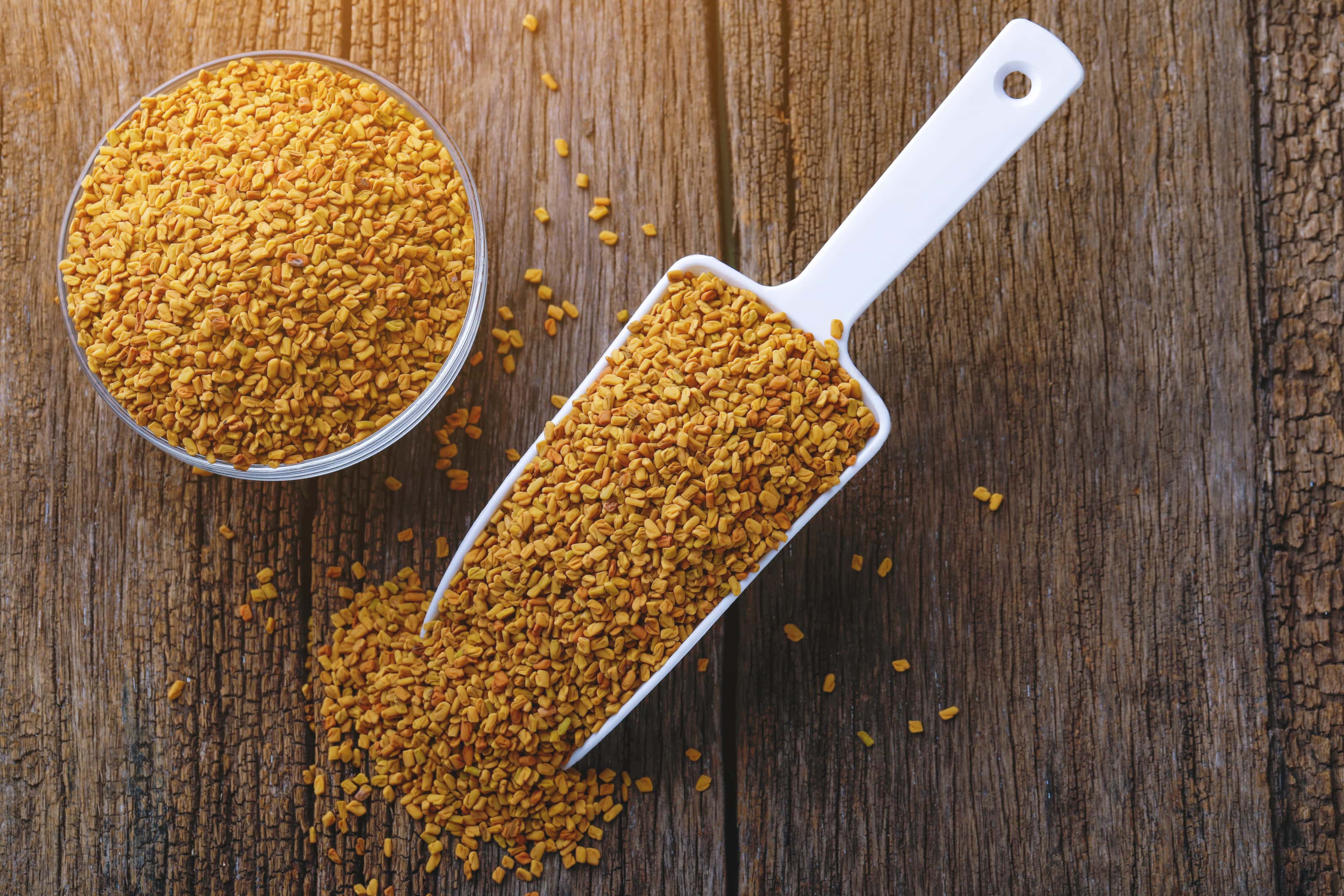 Fenugreek seeds glass bowl and spoon on wooden table