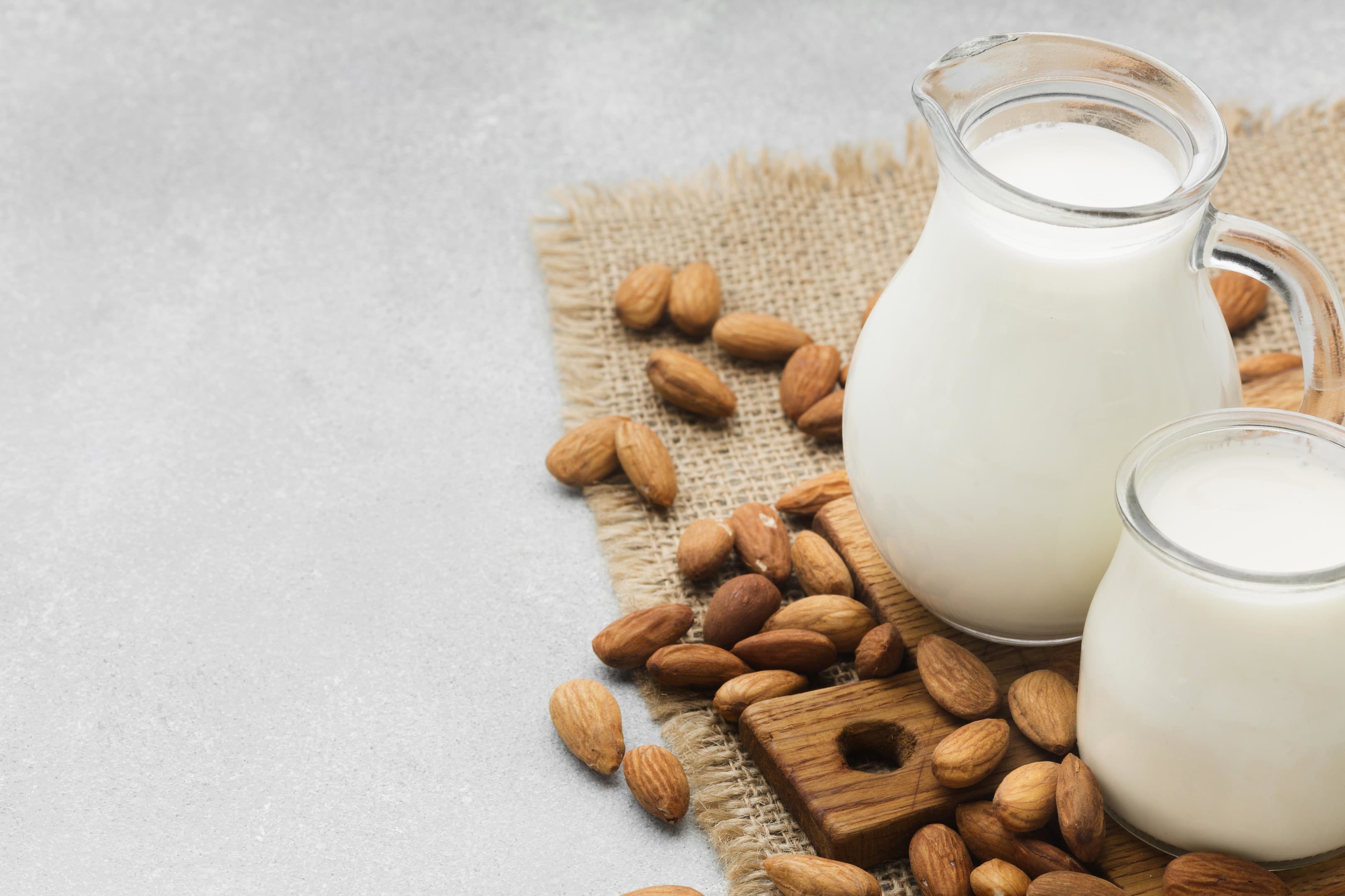 Fresh almond milk with almonds on white table