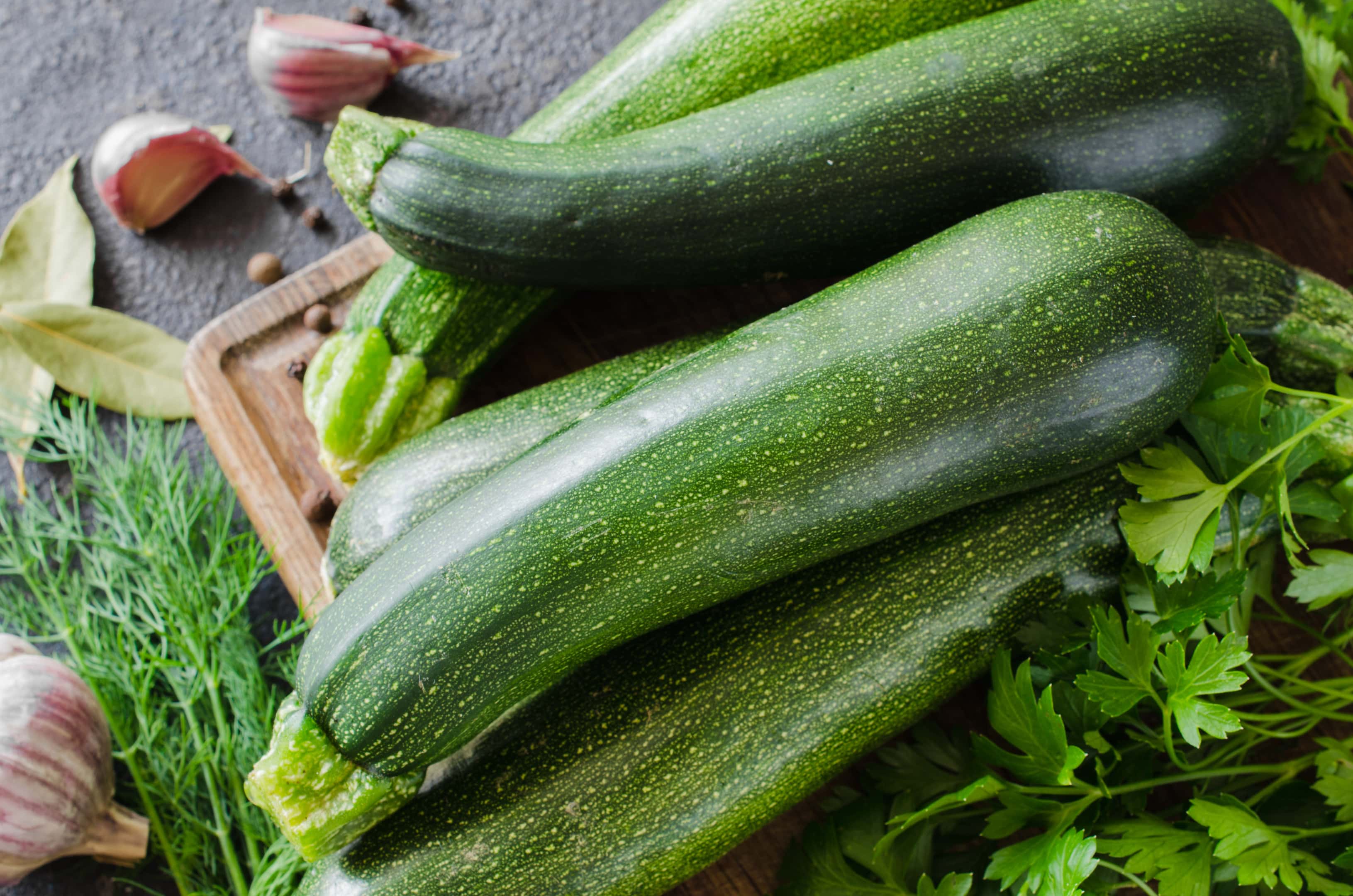 Fresh organic zucchini with parsley and herbs on wooden board