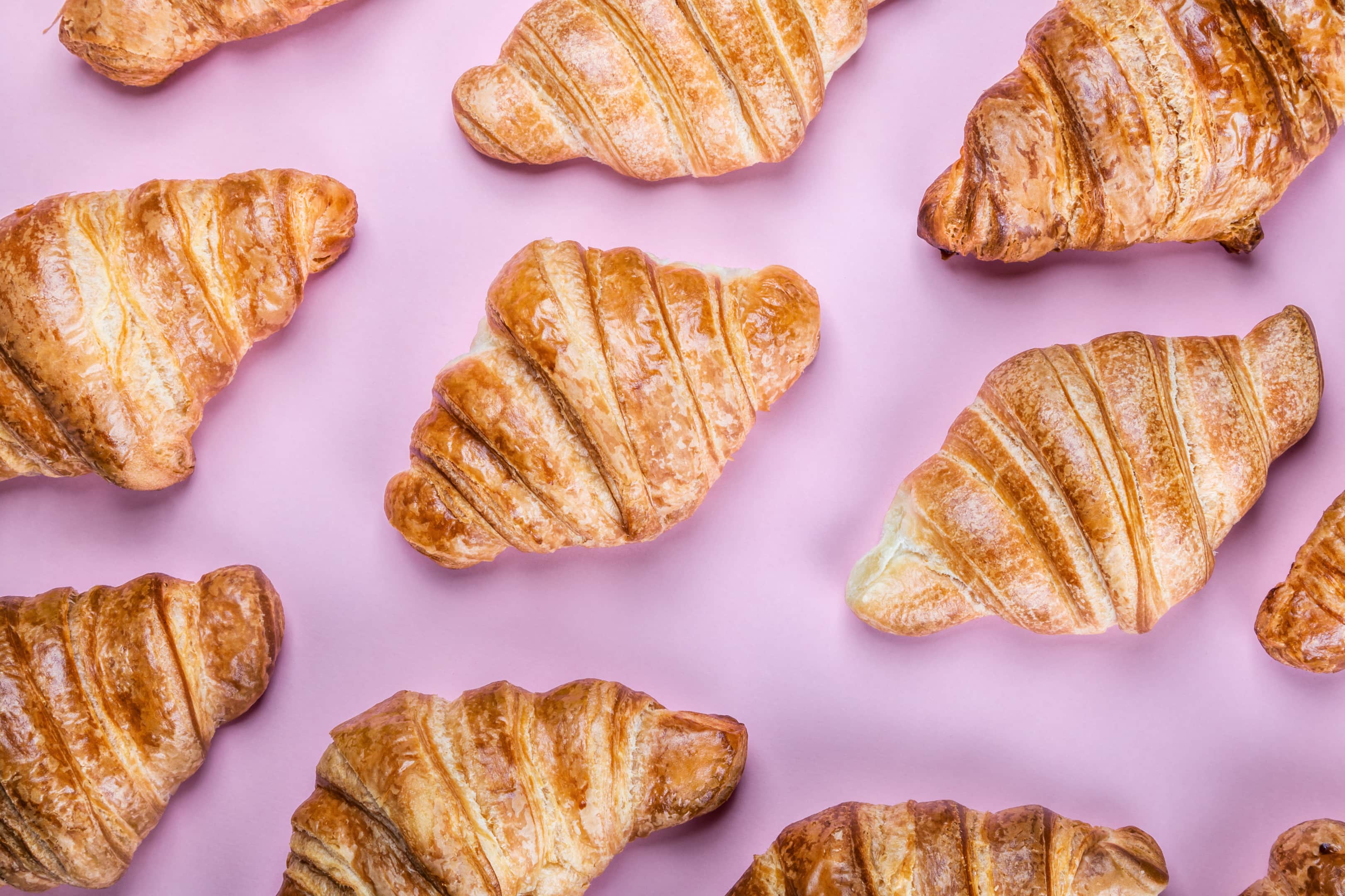 Freshly baked croissants on pink background