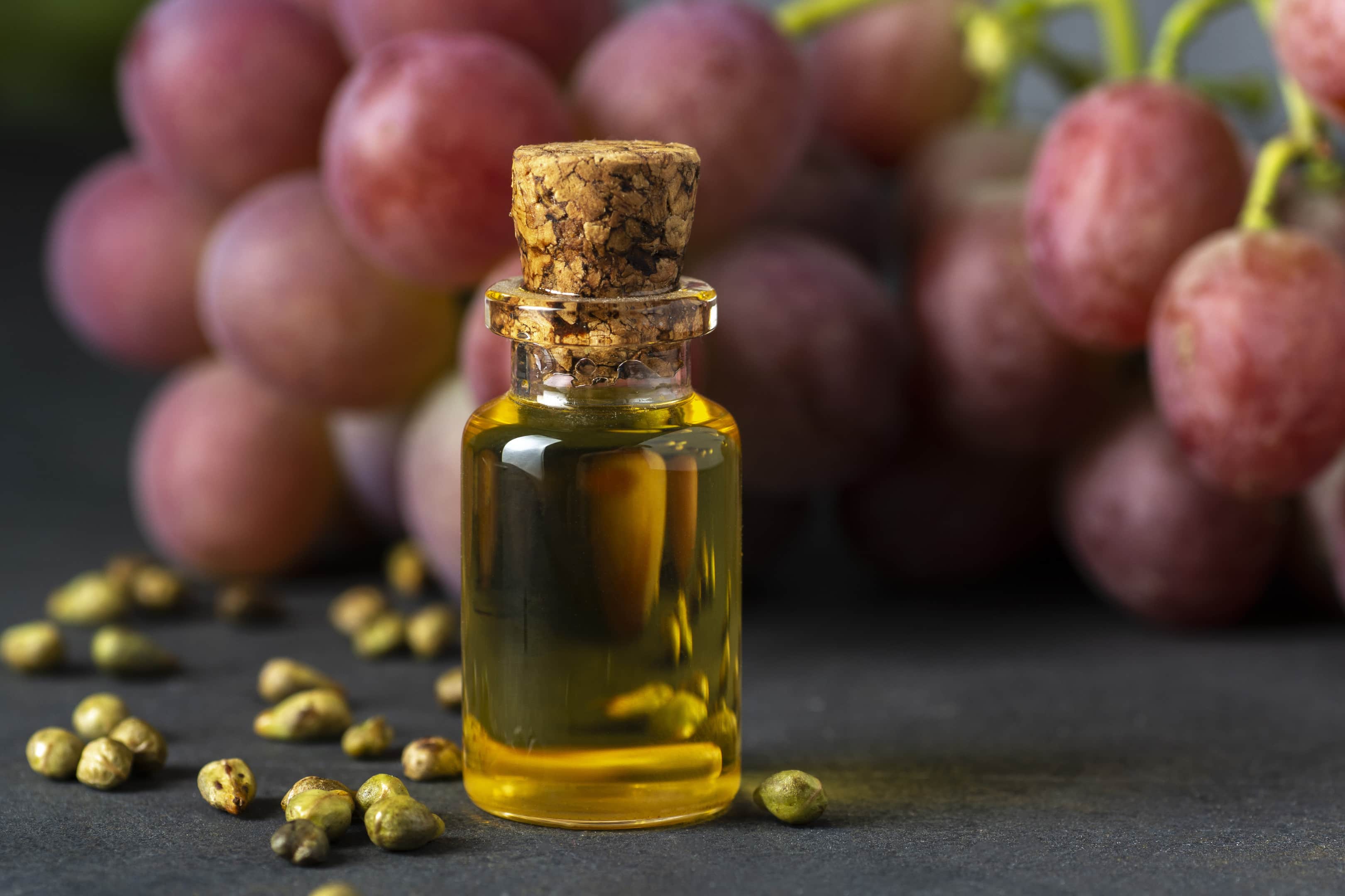 Grape seed oil extract in a glass bottle with fresh grapes