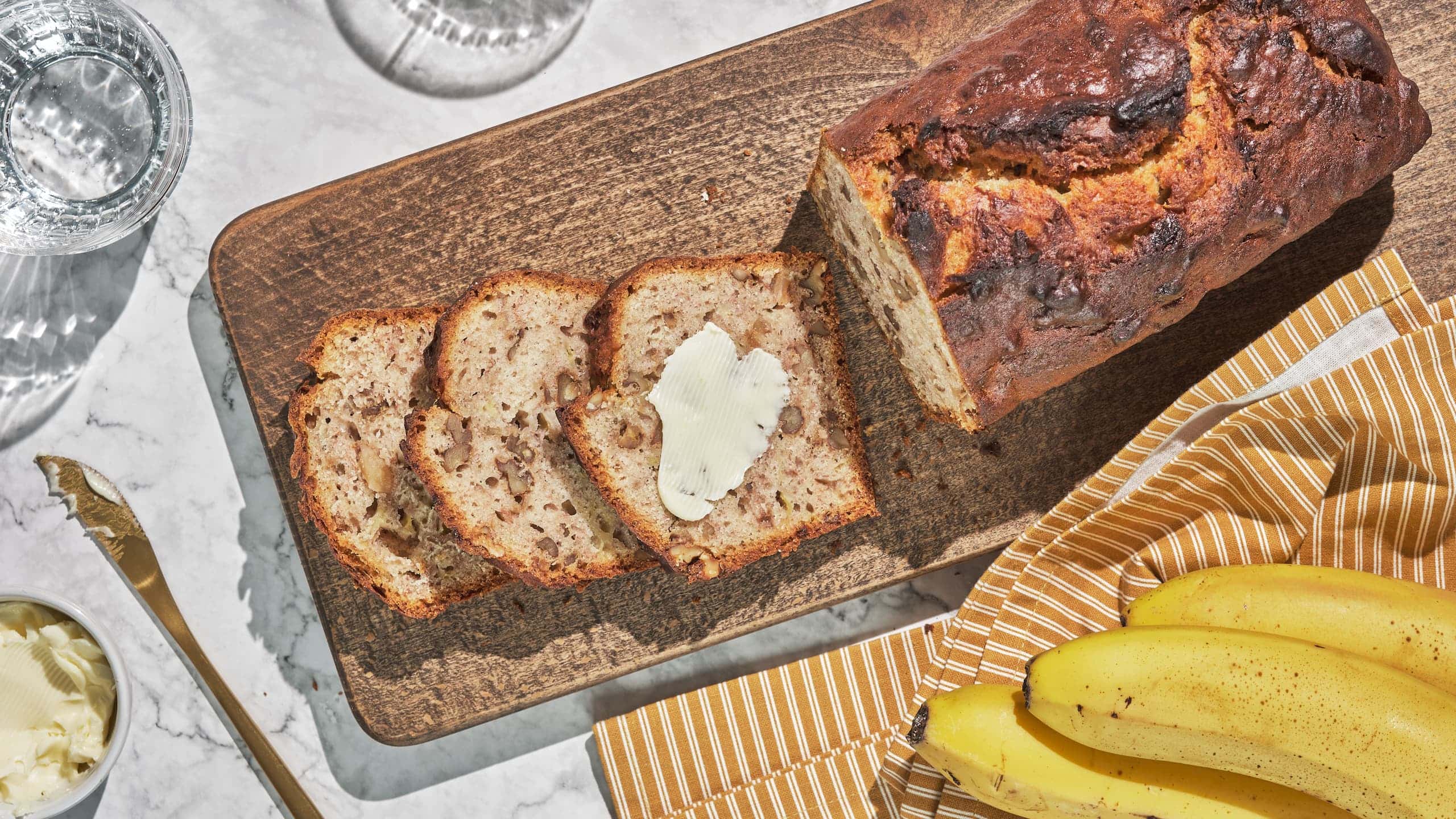 Banana bread slices on a cutting board with butter