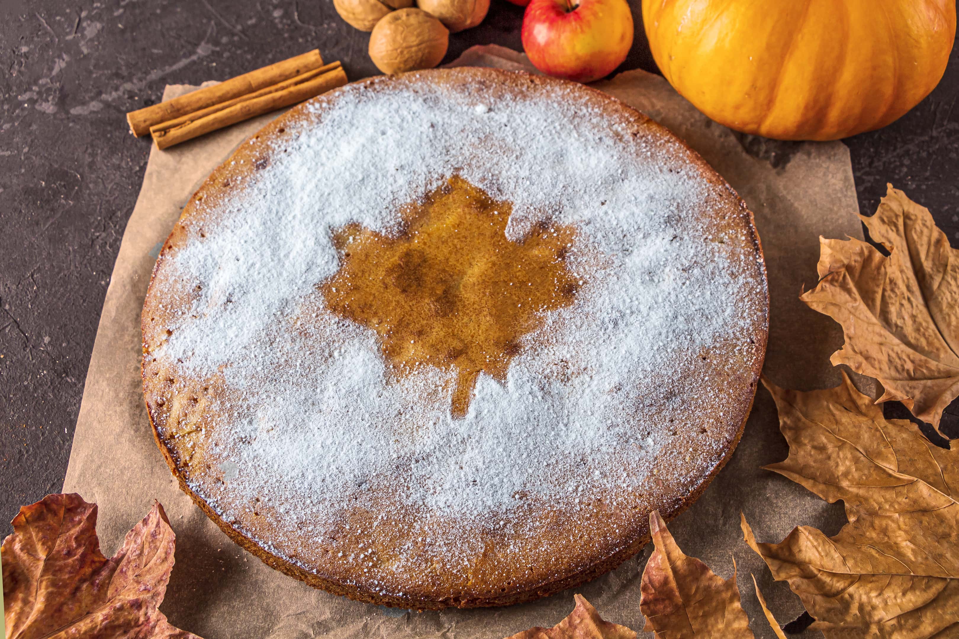 Homemade pie with maple sugar and maple leaves on rustic table