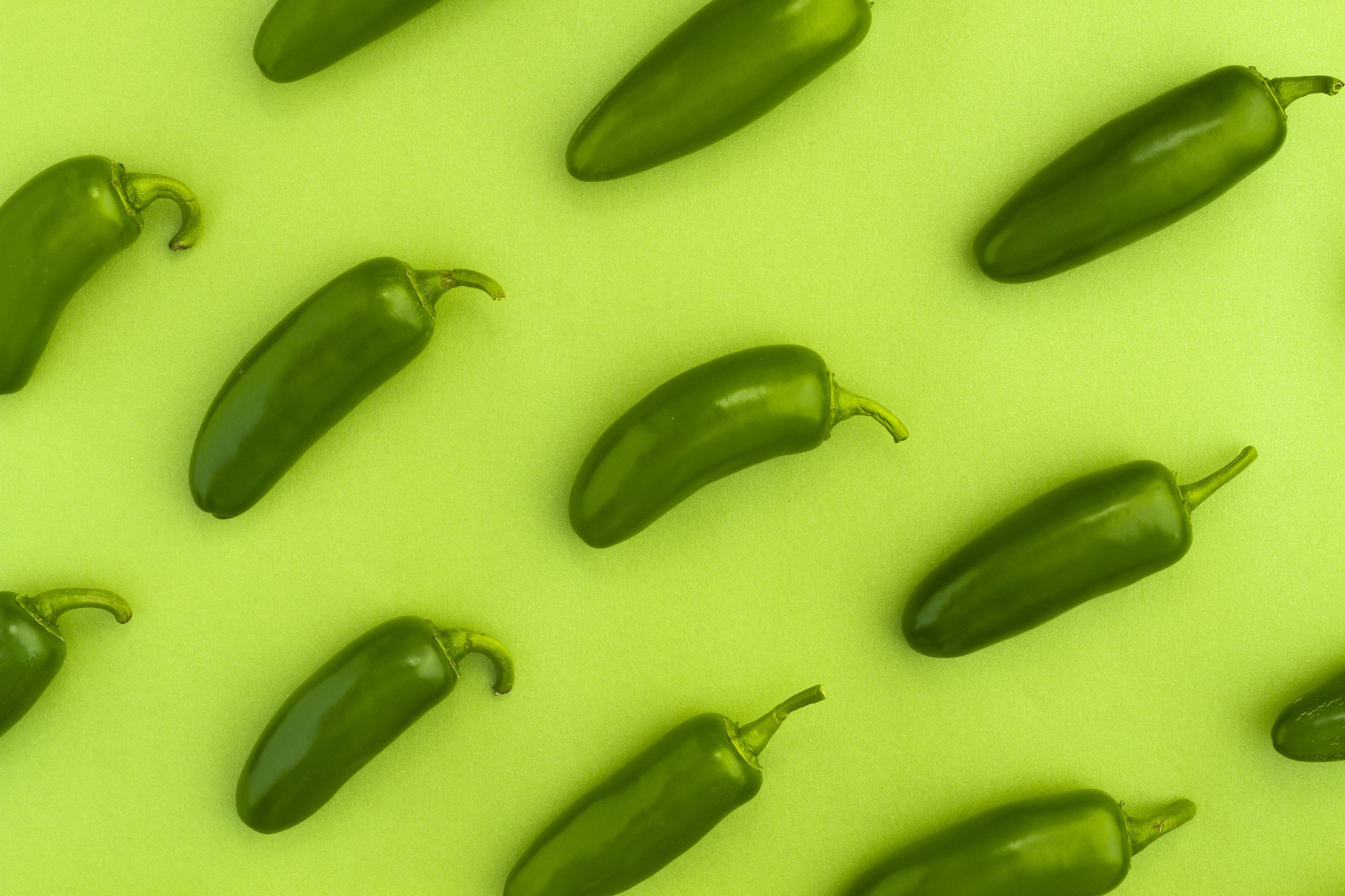 Jalapeño peppers on a green background