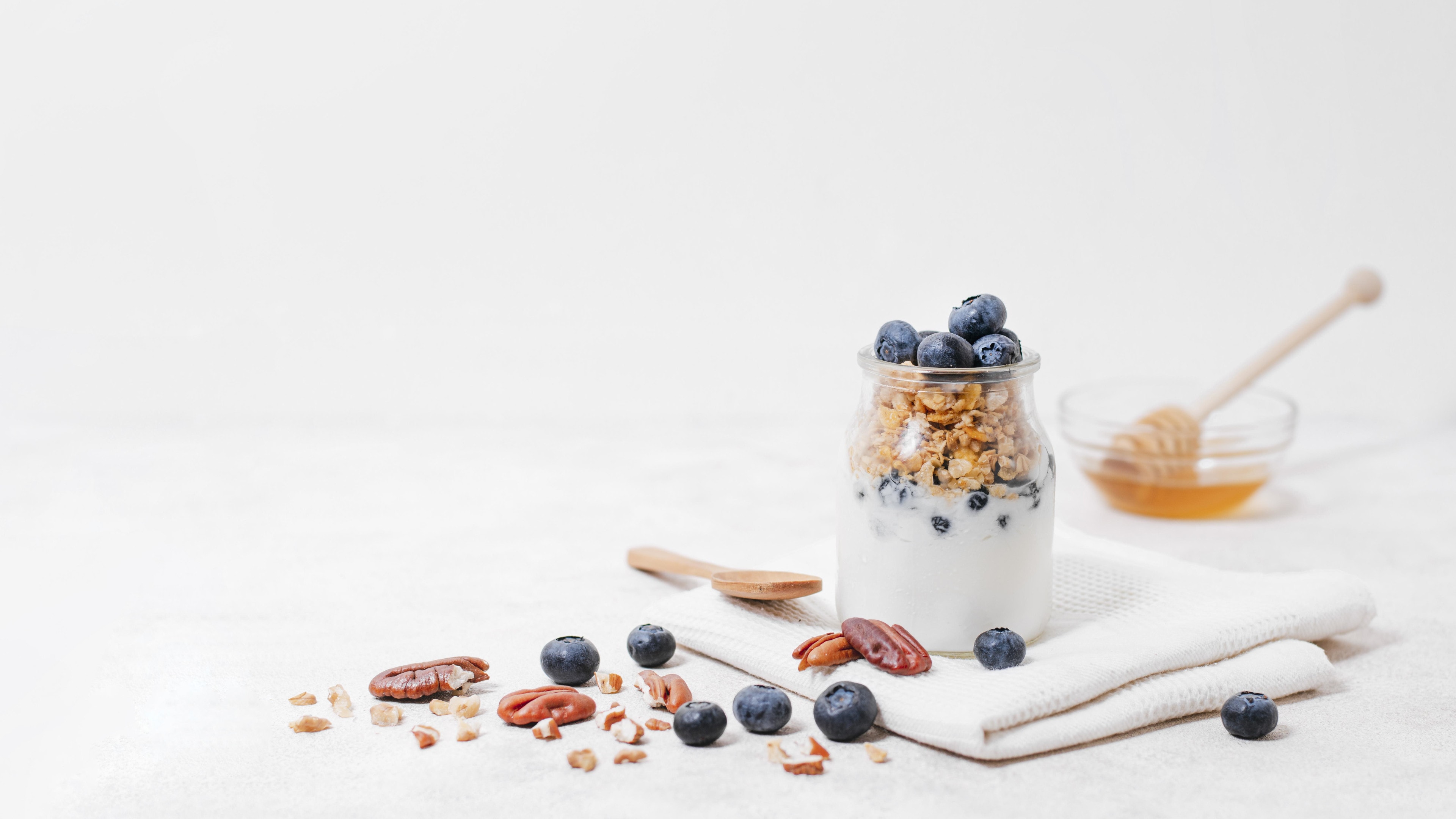 Jar filled with yogurt, granola and blueberries