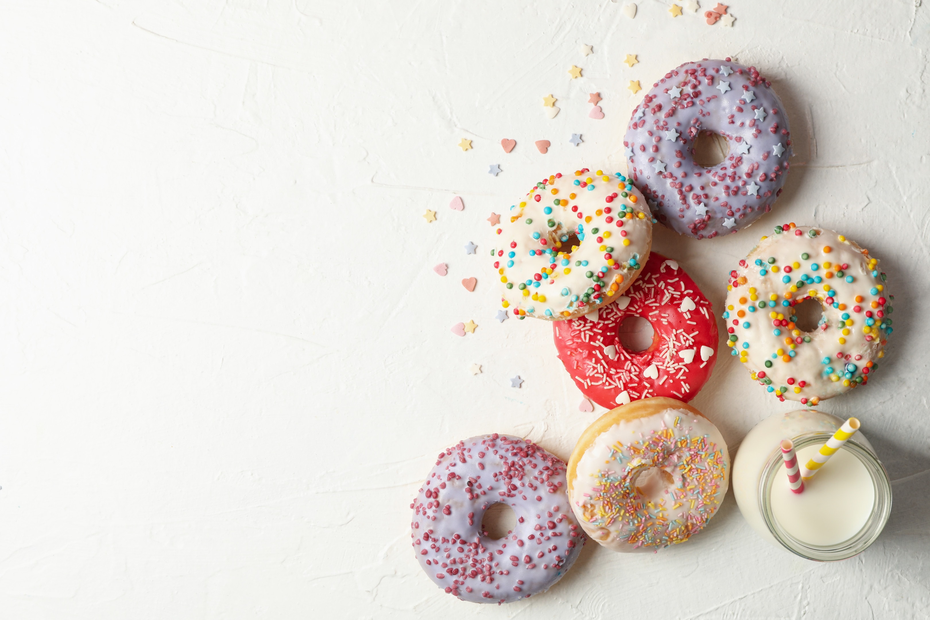 Milk and tasty donuts on white table