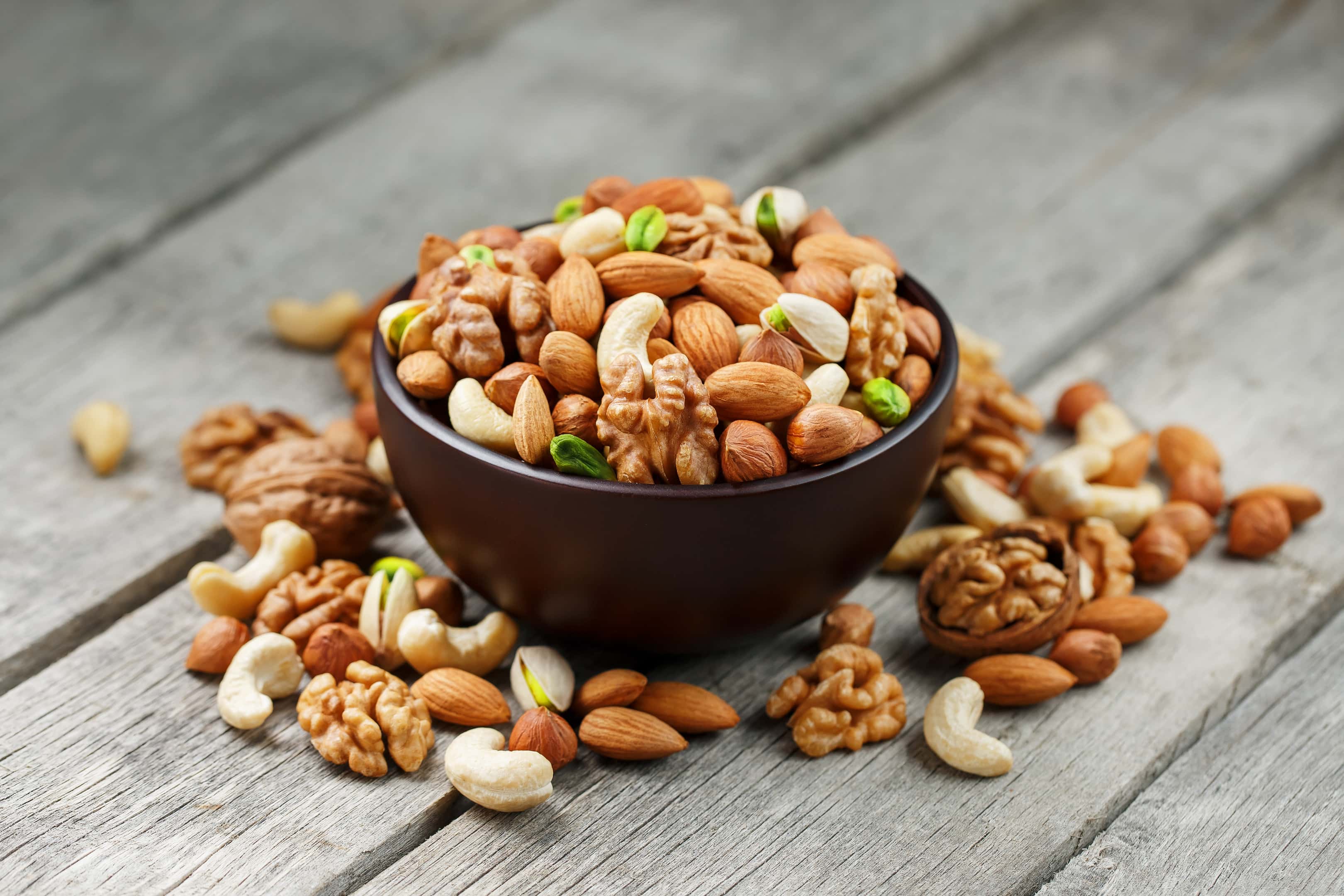 Mixed nuts in wooden bowl on wooden gray table