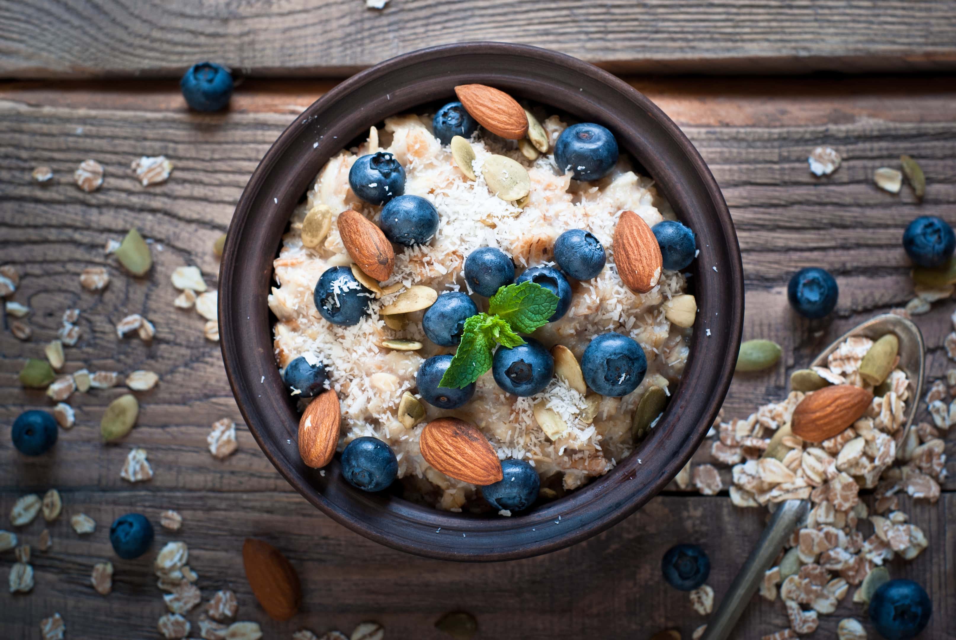 Oatmeal with blueberries, almonds, coconat and seeds at rustic wooden table