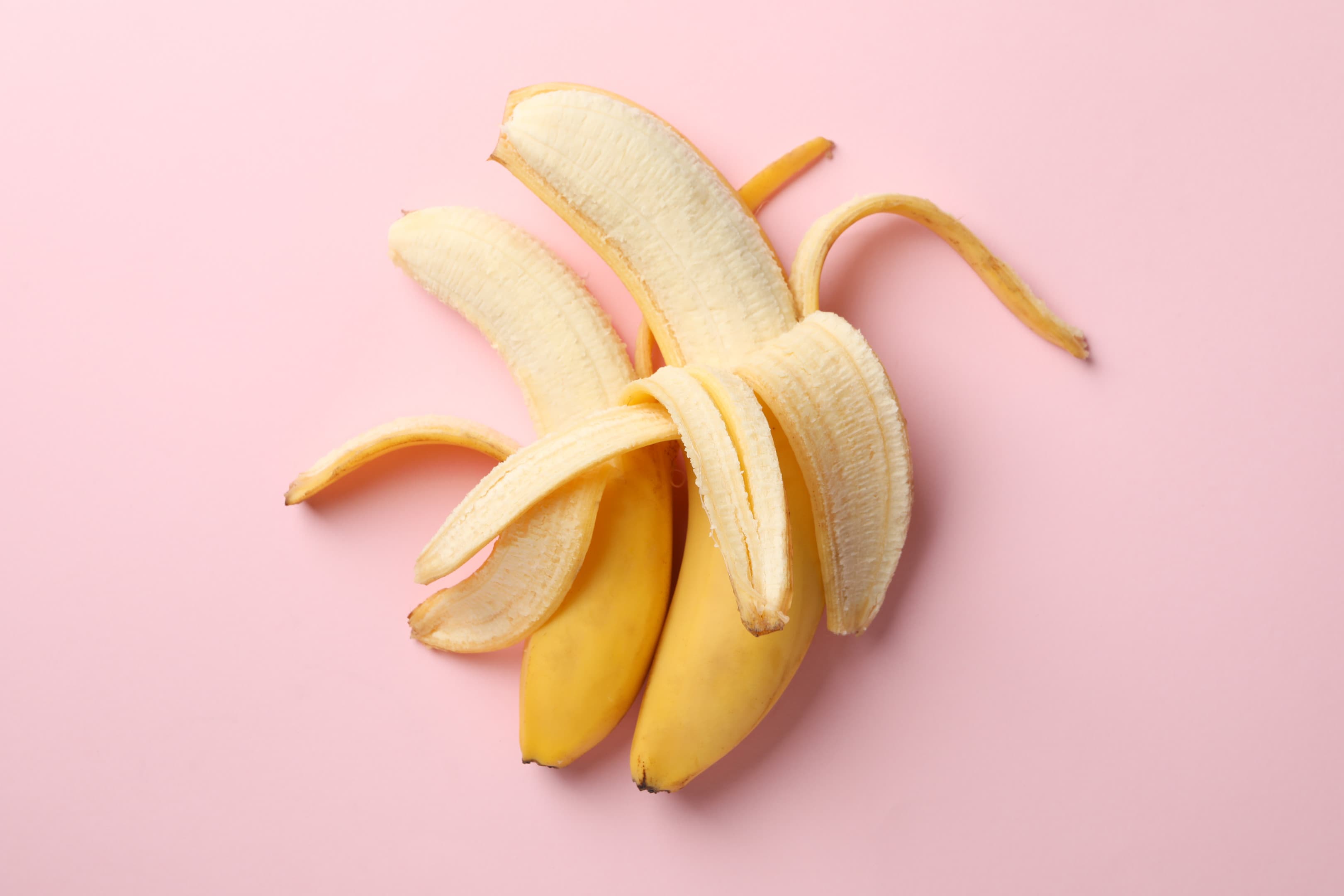 Opened bananas on pink table