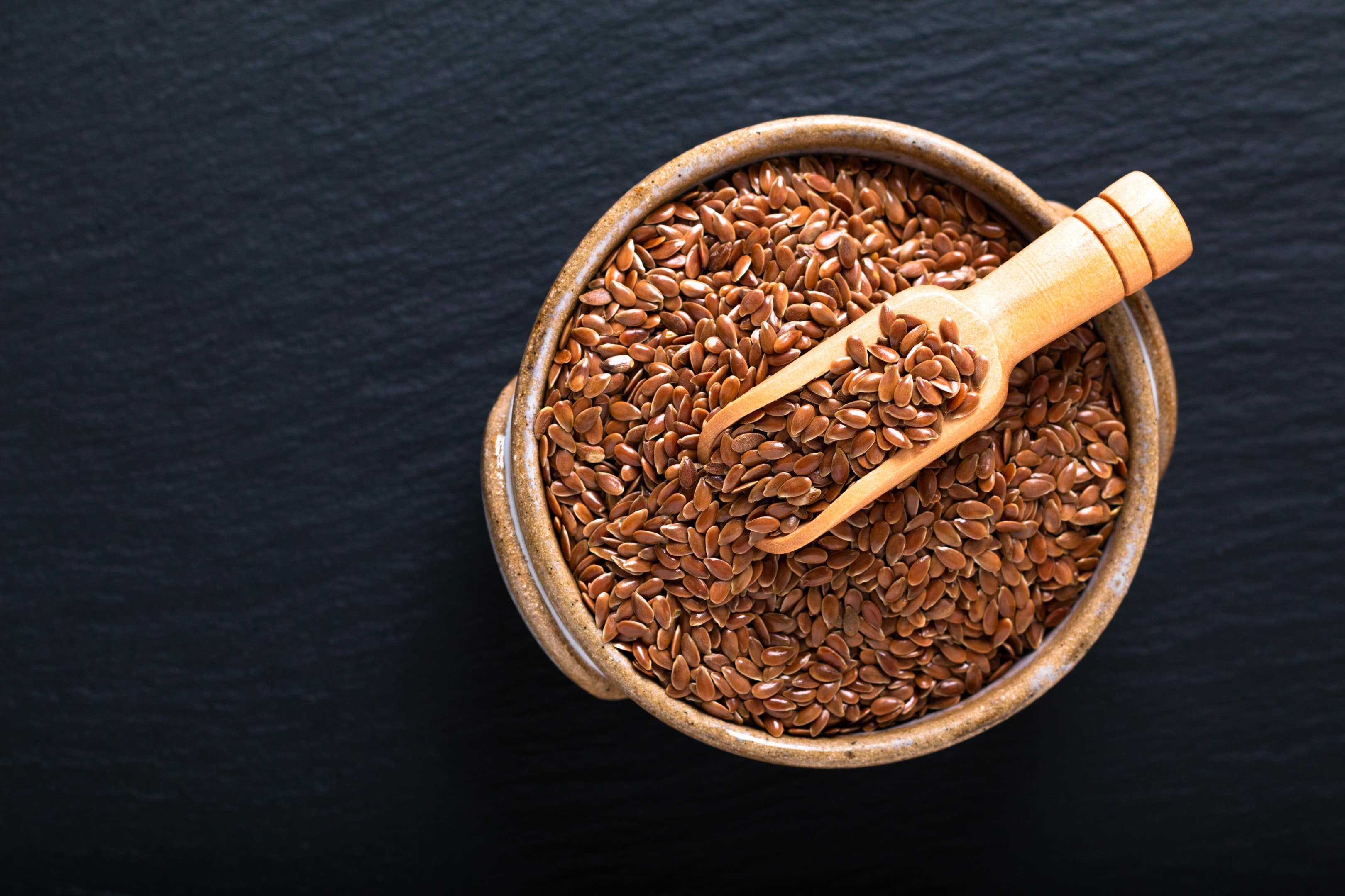 Organic flax seeds in ceramic bowl on black table