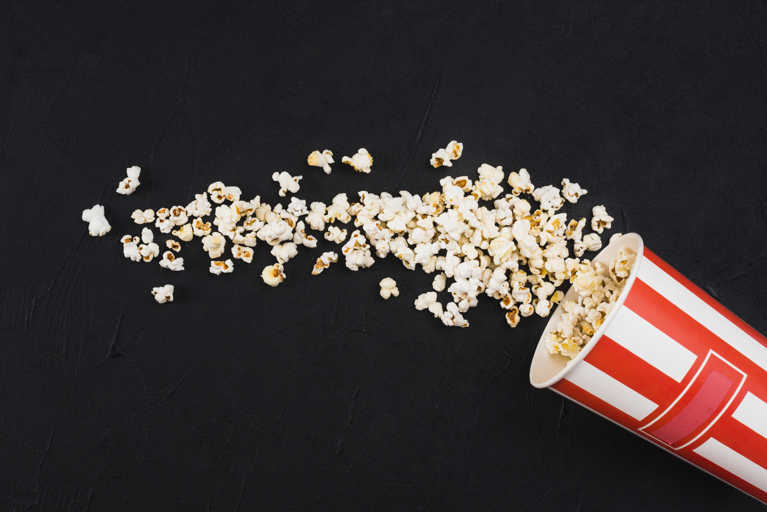 Popcorn spilled from striped on black background