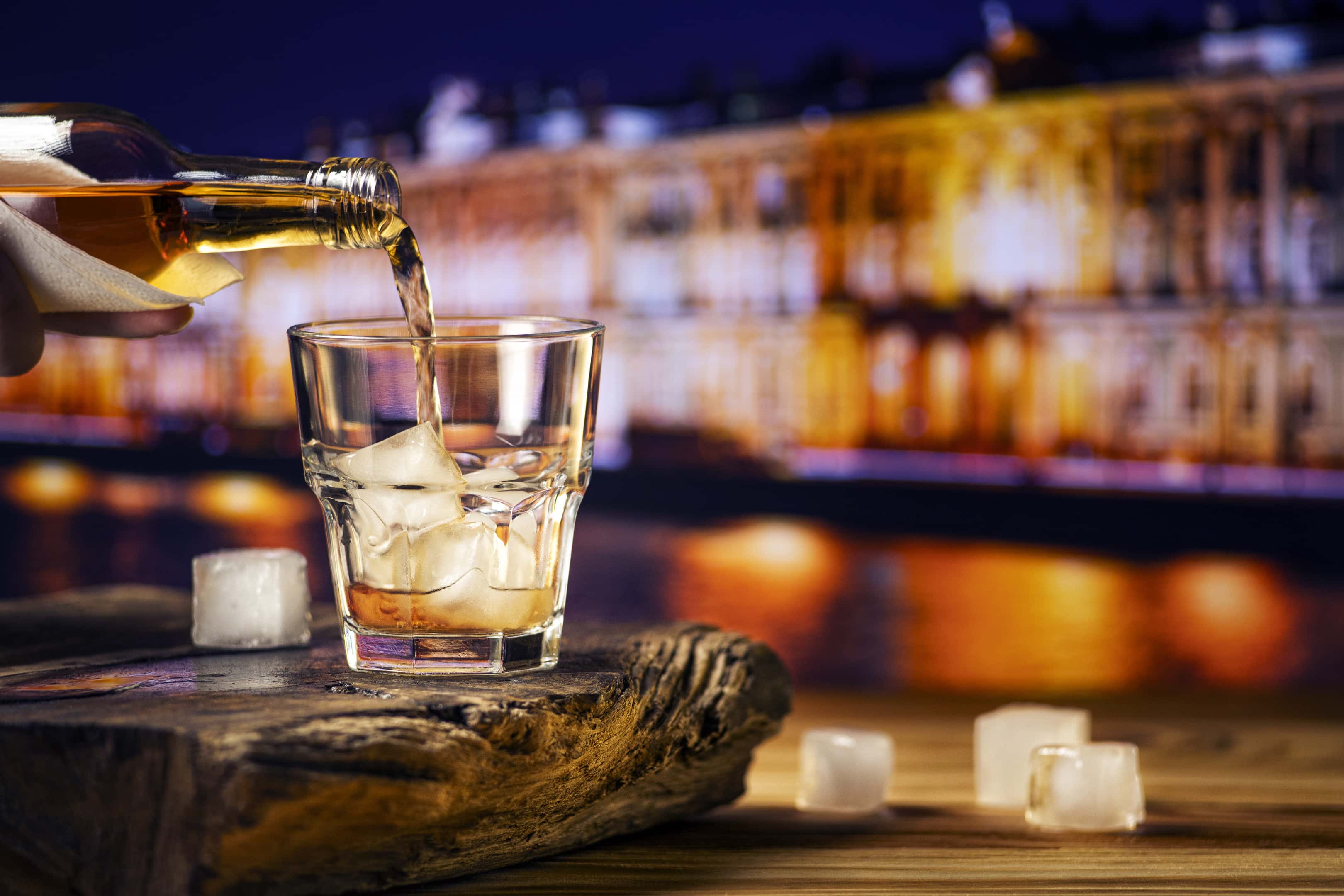 Pouring whiskey into glass with ice