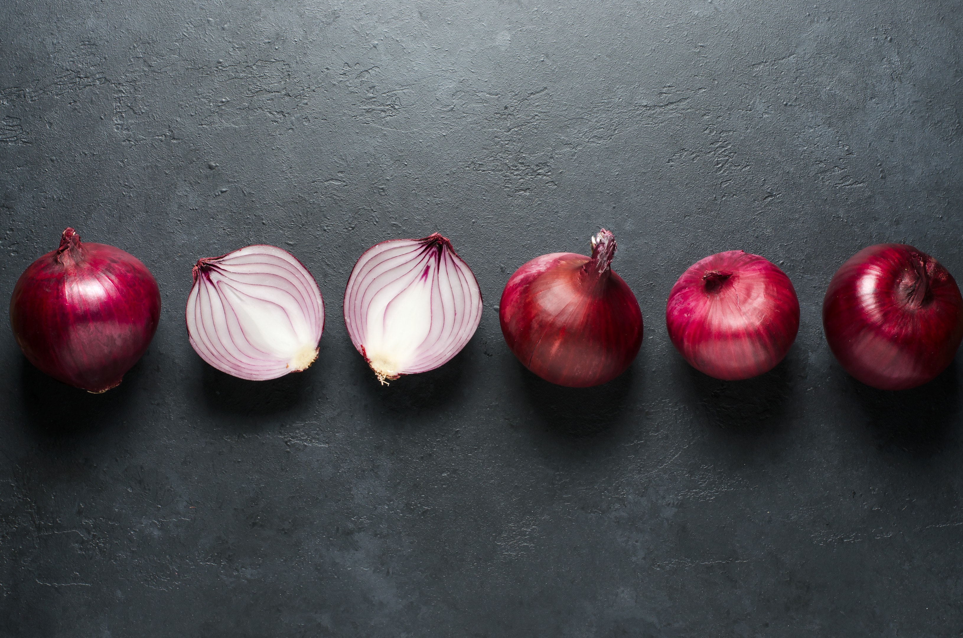 Red onion whole and sliced on black background